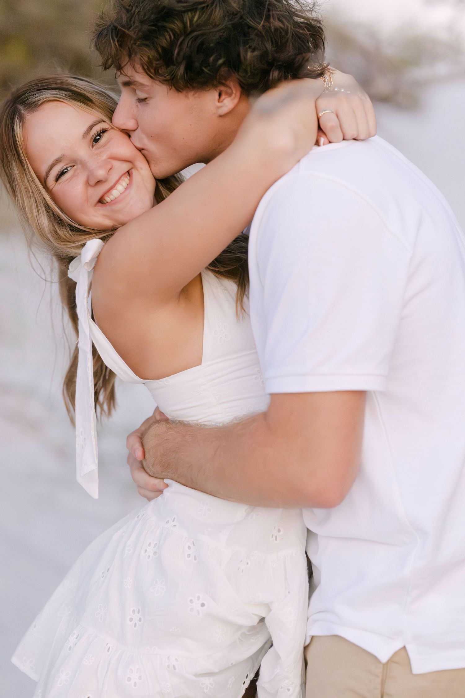 A couple in white clothing embrace lovingly while sharing a tender romantic moment together.