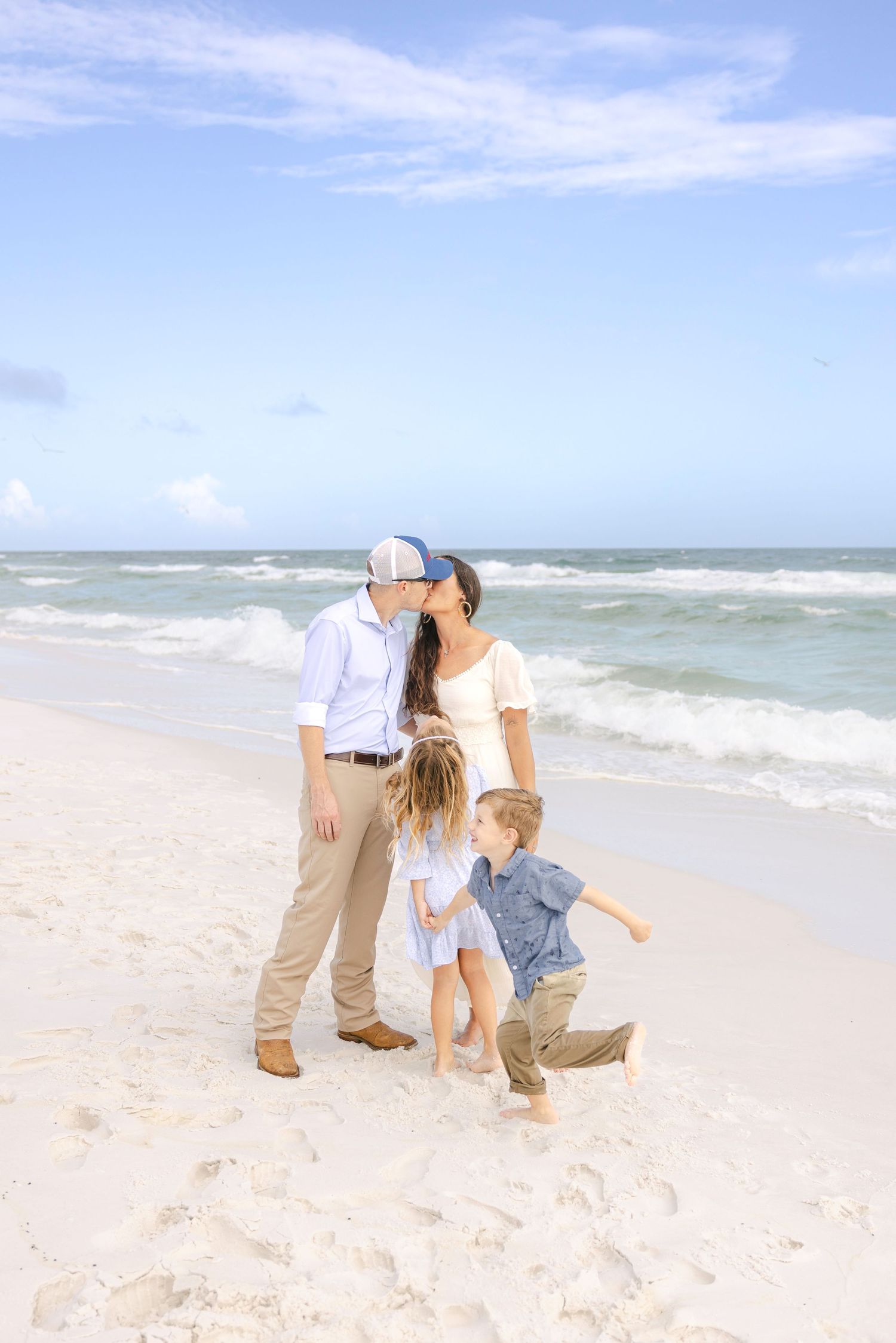 Playful beach photoshoot with couples dancing and embracing by the ocean waves.