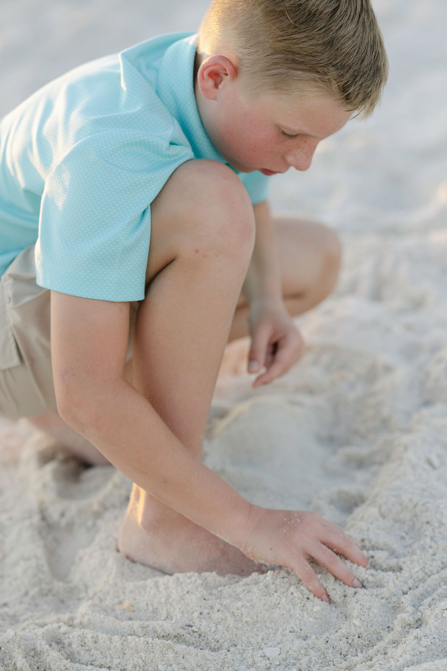 Children playing in white sand on a sunny beach.