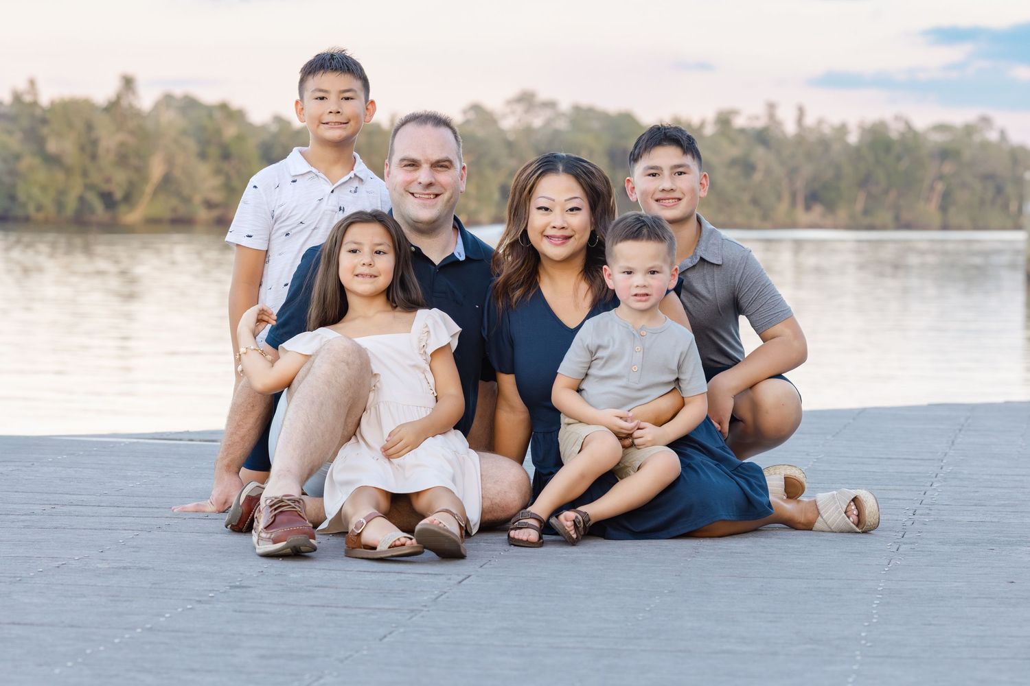 Family relaxes together on sandy beach shore during golden hour outdoor photo session.