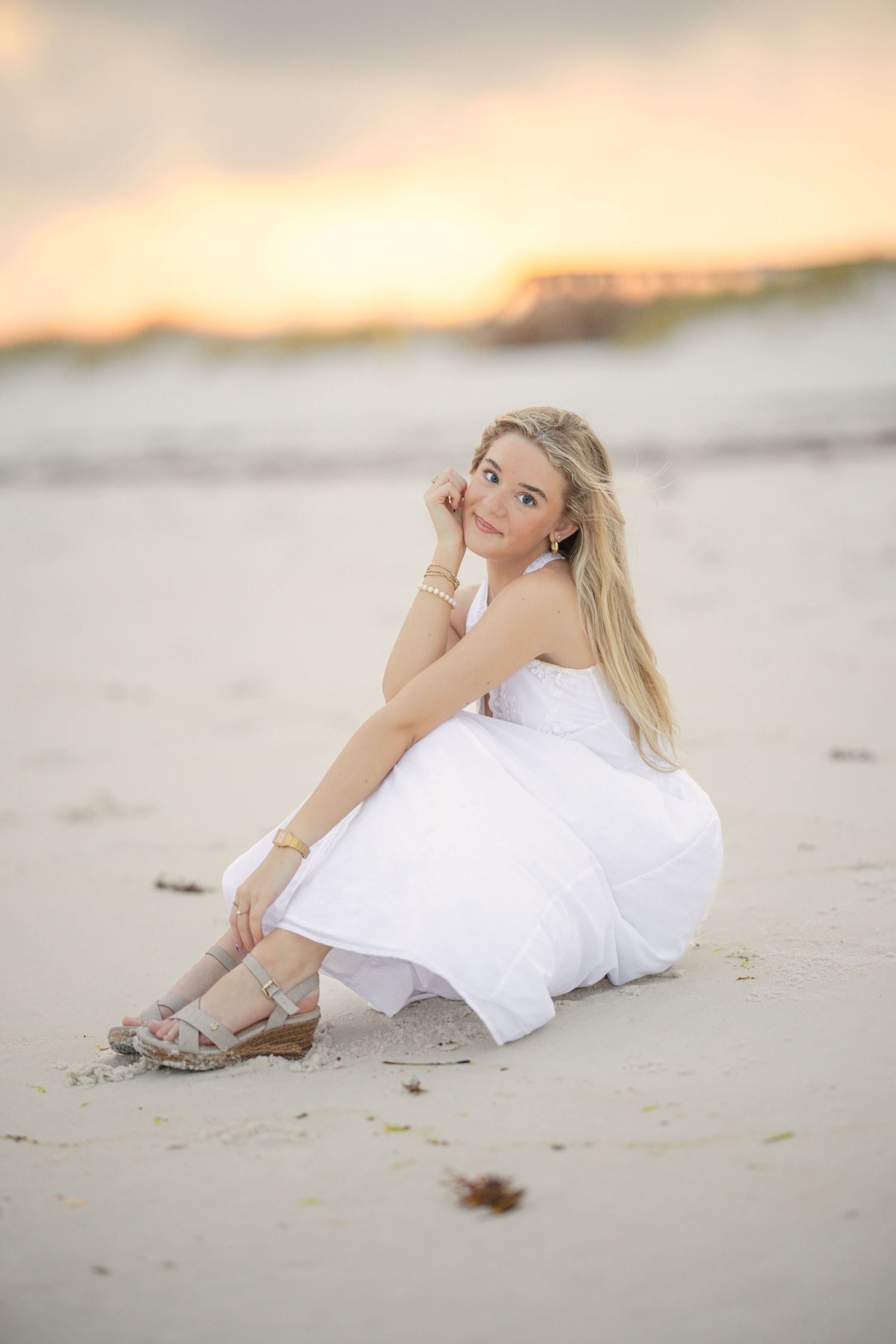 Soft sunset light illuminates a beach portrait in a flowing white dress.