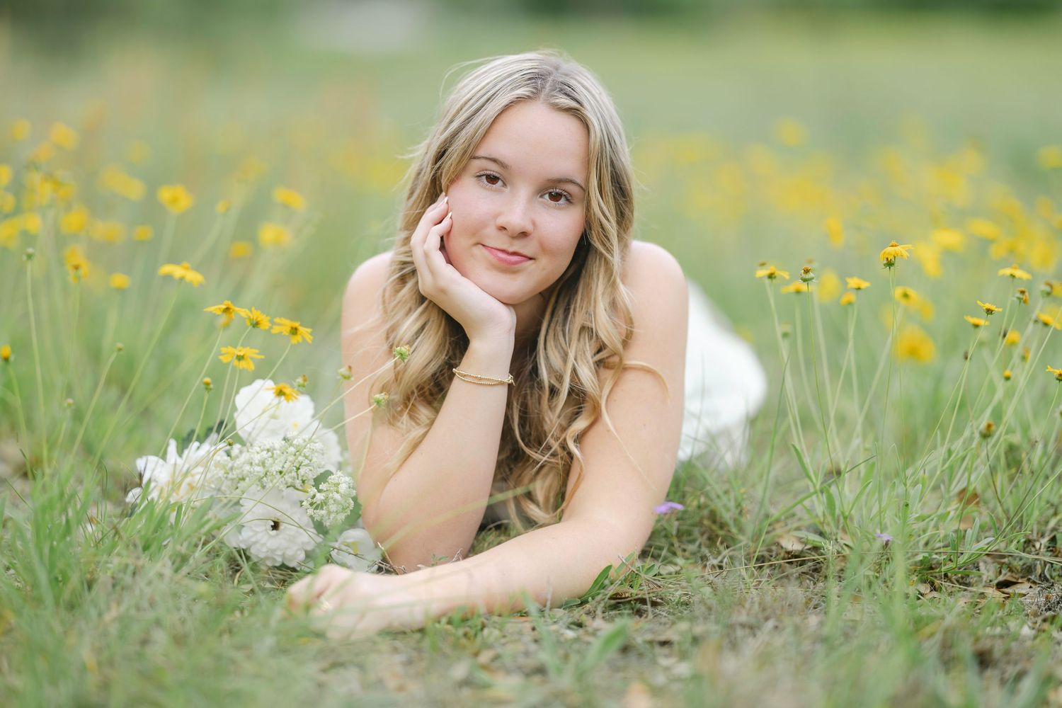 Young woman lying in a meadow of yellow wildflowers on a sunny spring day.