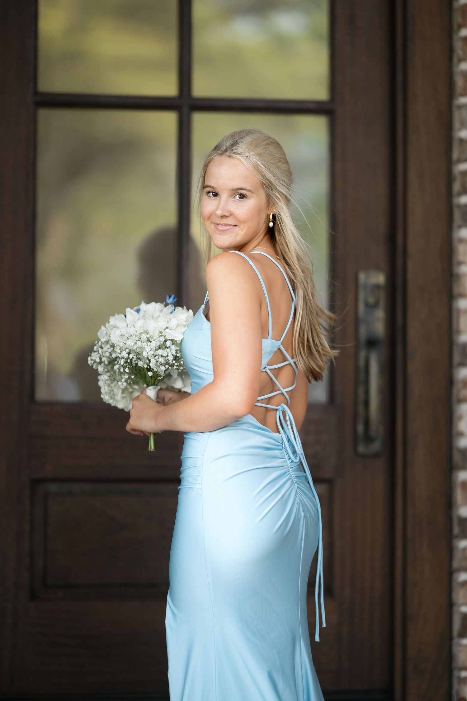 A light blue dress with strappy back detail captured against wooden doors and windows.
