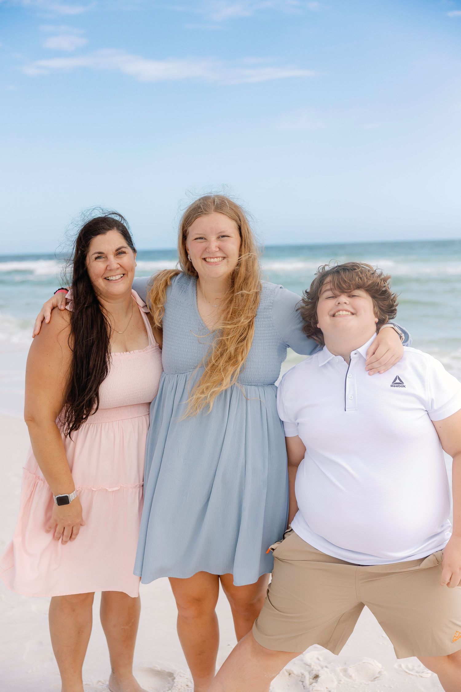 Four friends enjoying a sunny day together at the beach wearing casual summer outfits.