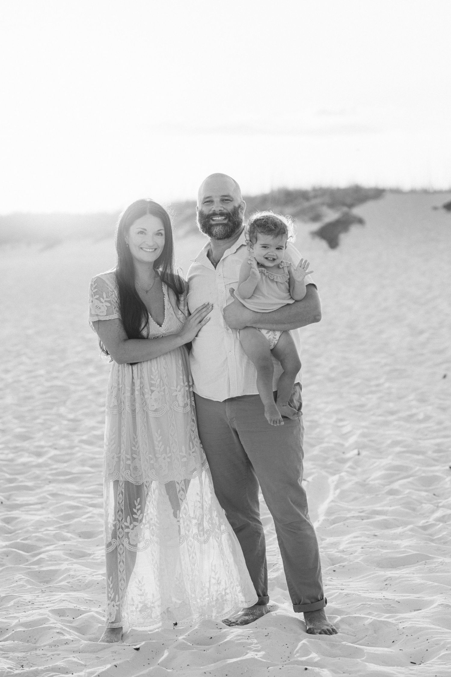 Family enjoying a candid black and white photoshoot moment together on a pristine white sandy beach.