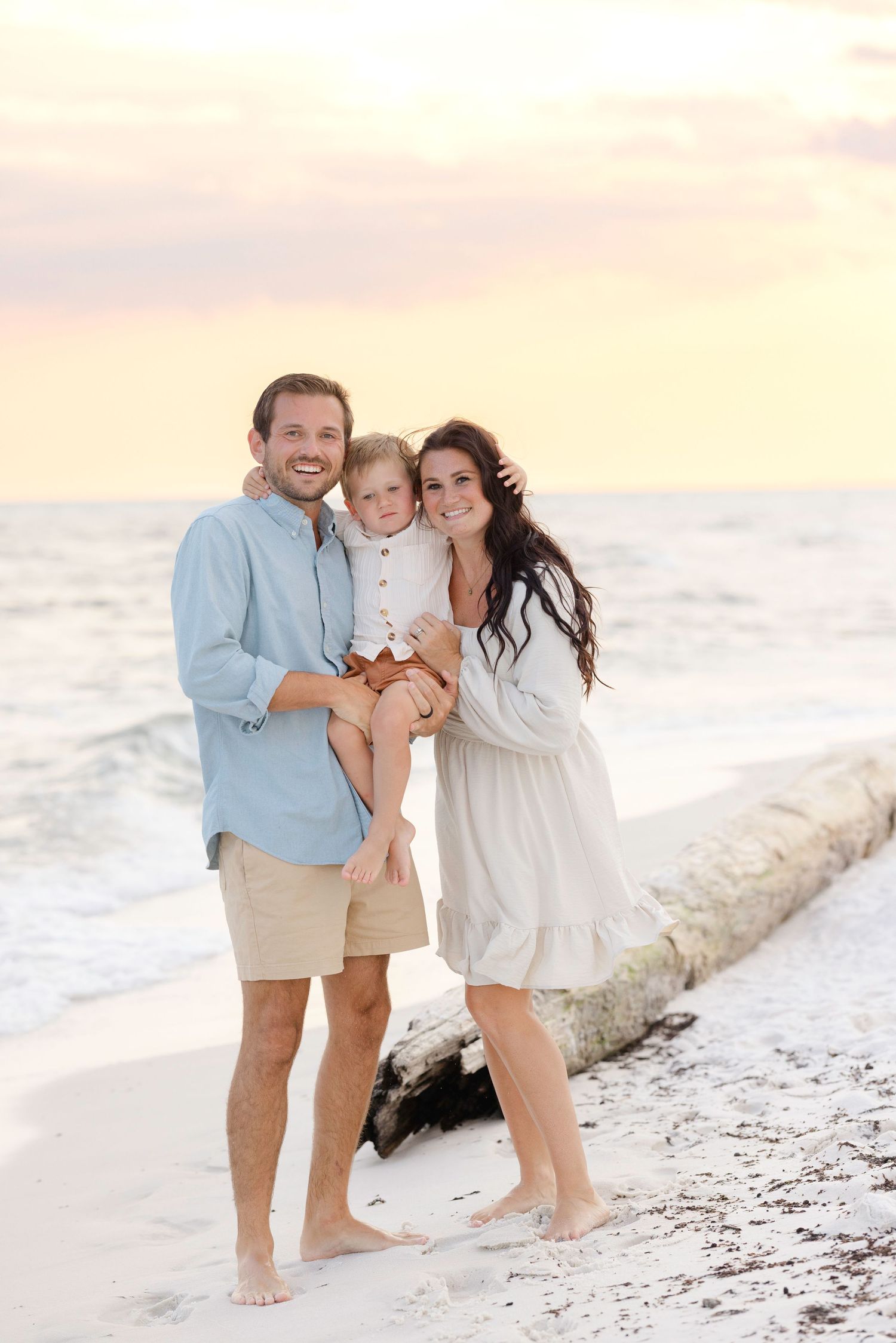 Happy moment captured of family embracing on pristine beach during golden hour.