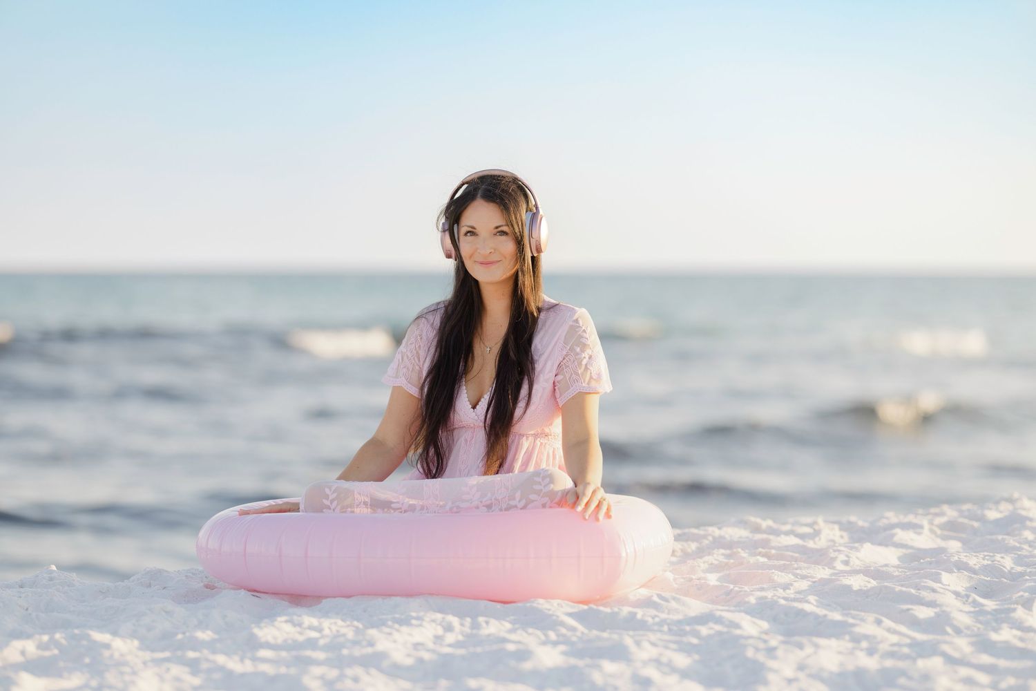 A series of images shows a person in a pink swimsuit sitting on pink float by the ocean at sunset.