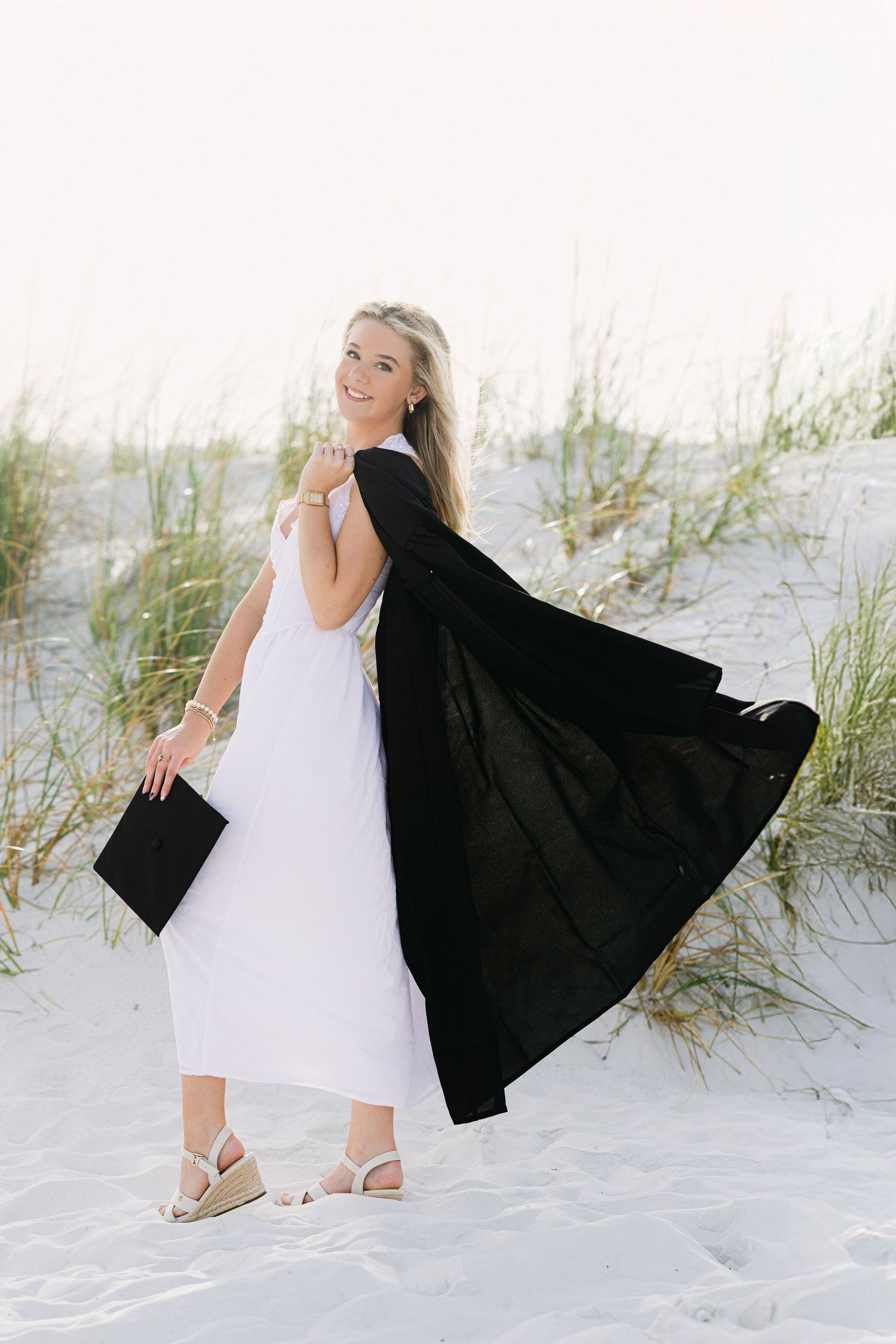 A series of beach portraits showing a white dress and black graduation gown against sand dunes and sea grass.