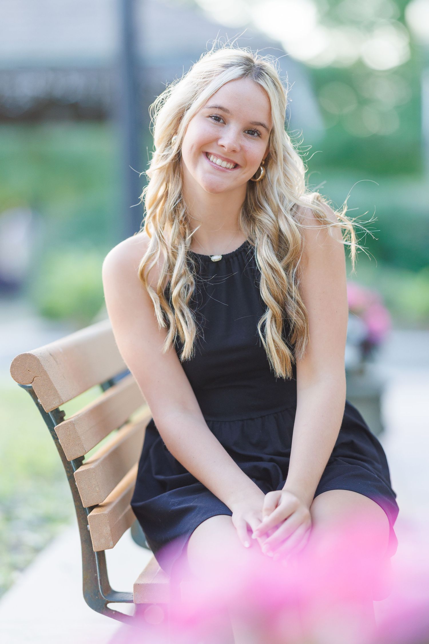 A posed portrait session with a black sleeveless top and soft natural lighting in an outdoor garden setting.