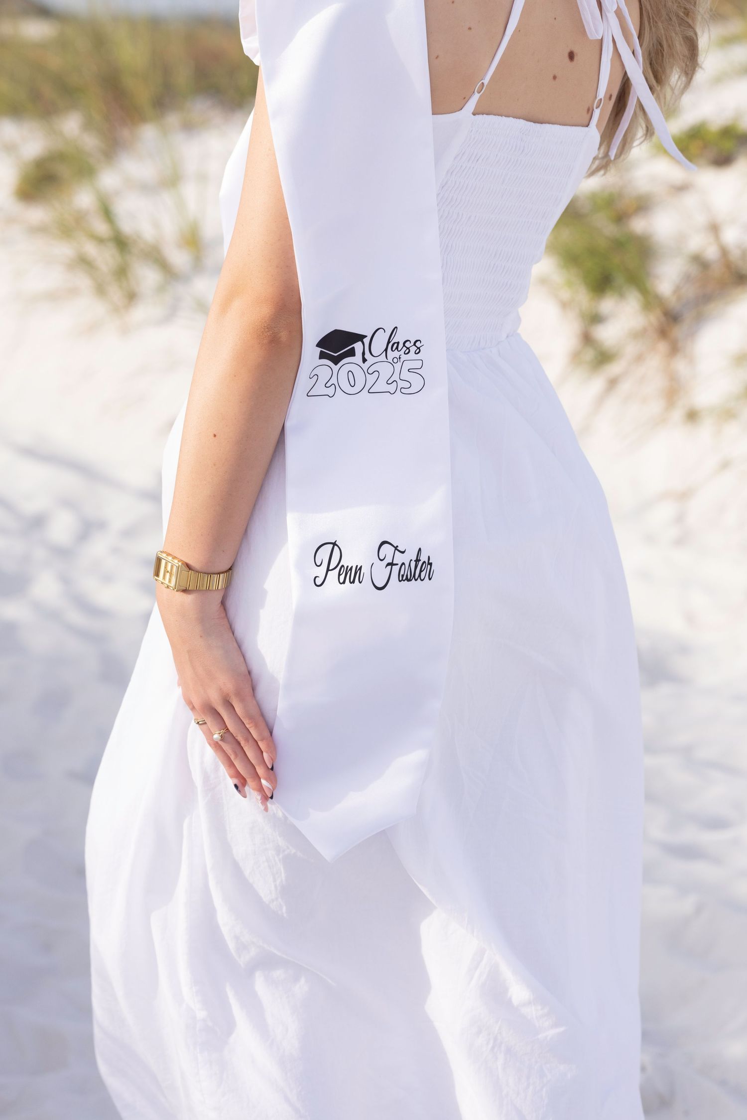 Close-up of white graduation dress with Class of 2023 emblem and name embroidered.