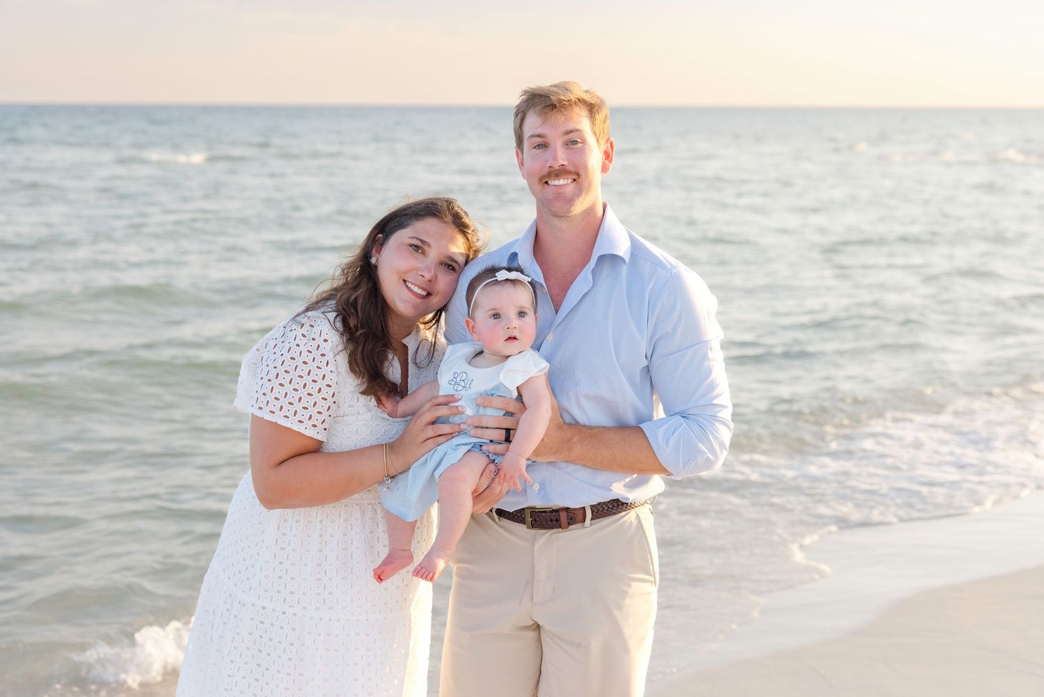 Happy family shares tender moments together during a sunset beach photoshoot in casual attire.