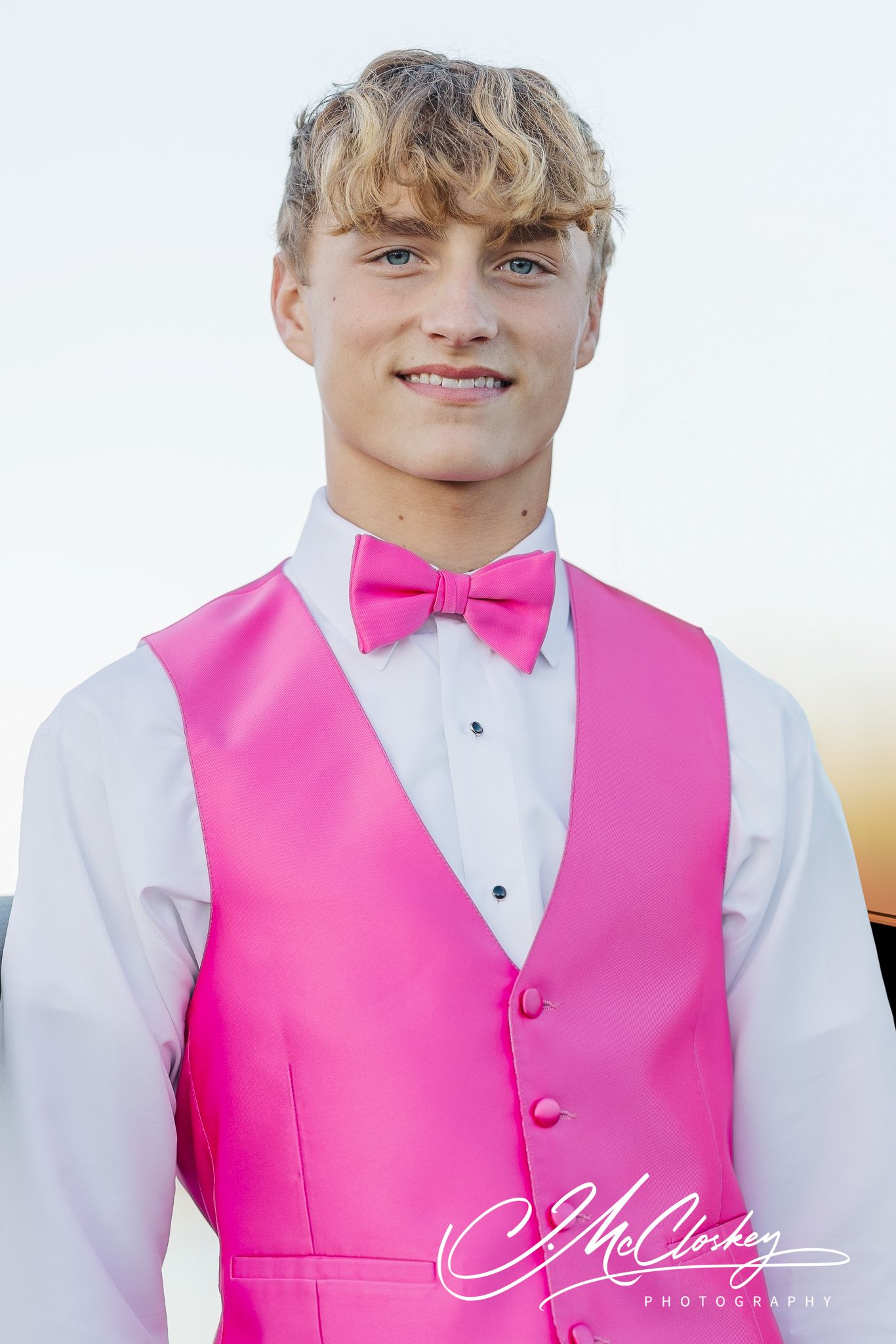 Four people in bright pink vests with white dress shirts and bow ties standing in a row at a formal event.