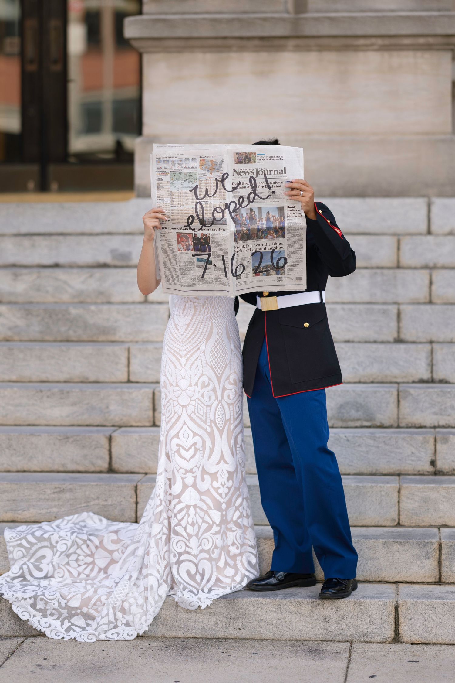 Eloping couple in wedding attire hold newspaper announcing their elopement on 7/16/26.