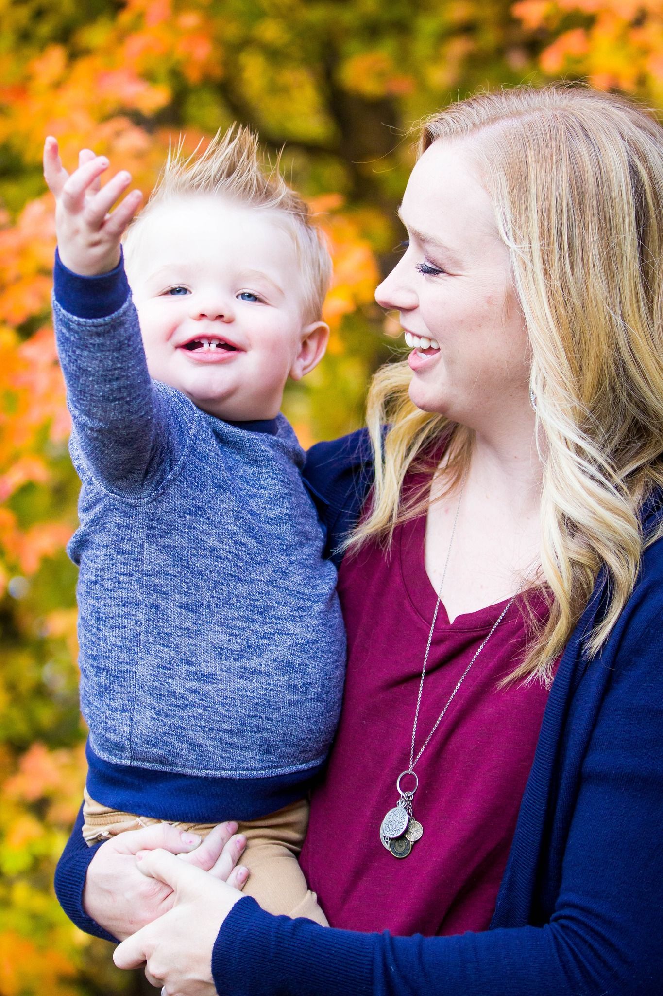 Joyful outdoor family portrait with vibrant fall foliage in background.