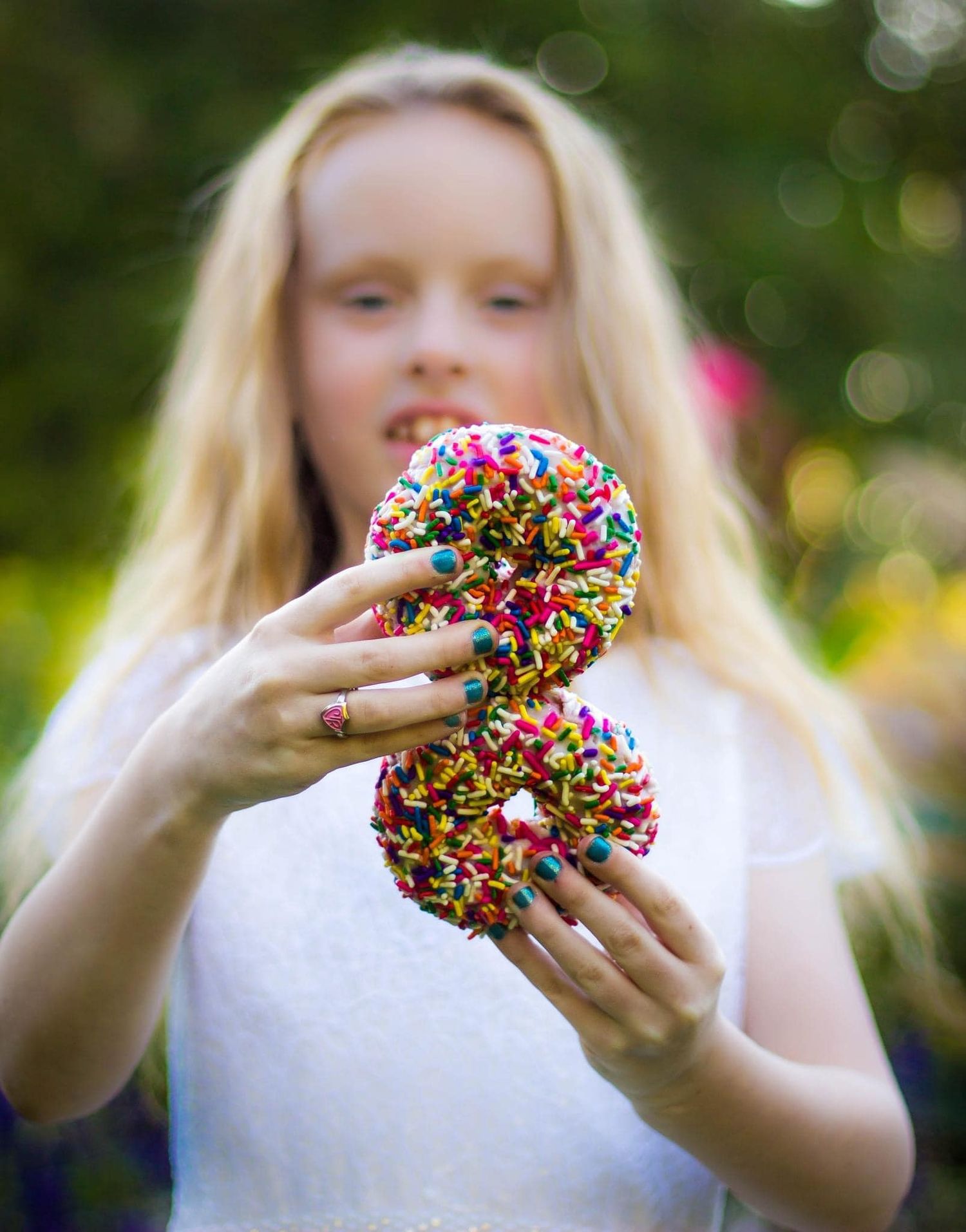 Close-up shots of colorful sprinkle-covered donuts being held against a bokeh background.