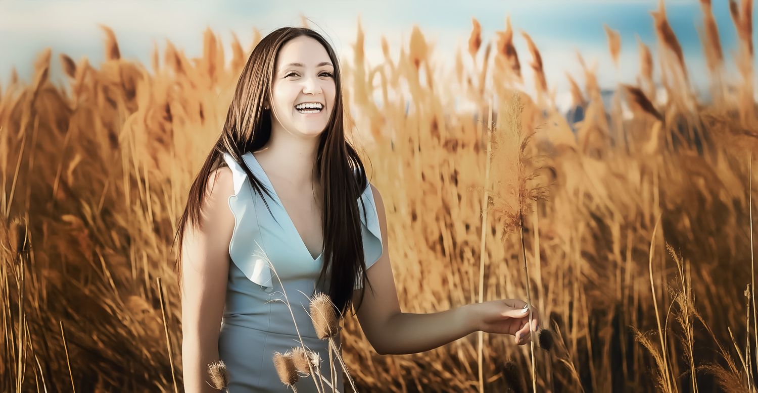 Woman dancing joyfully through tall grass during golden hour.