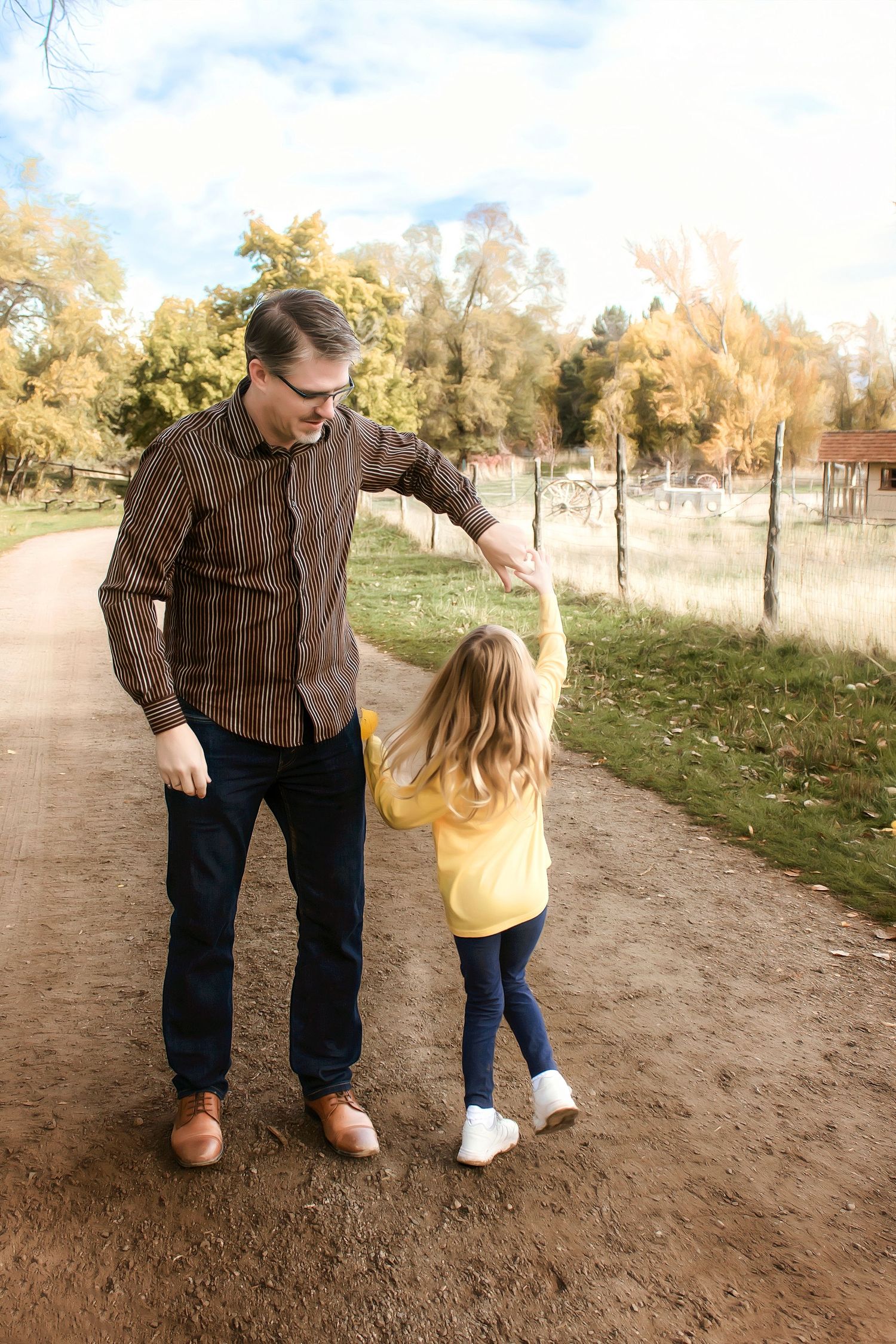 Two people walking together on a dirt path during a sunny autumn day.
