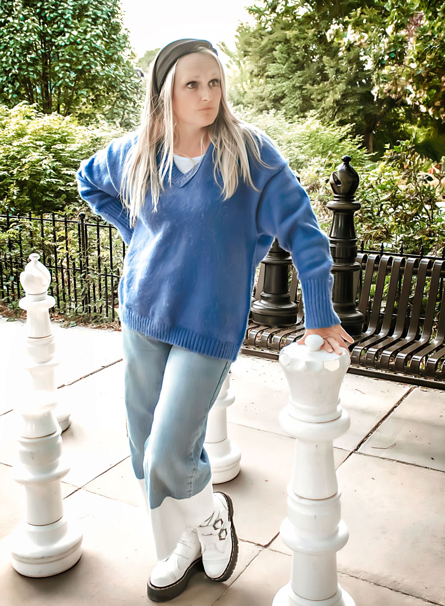 A person interacts with life-sized chess pieces on an outdoor patio.