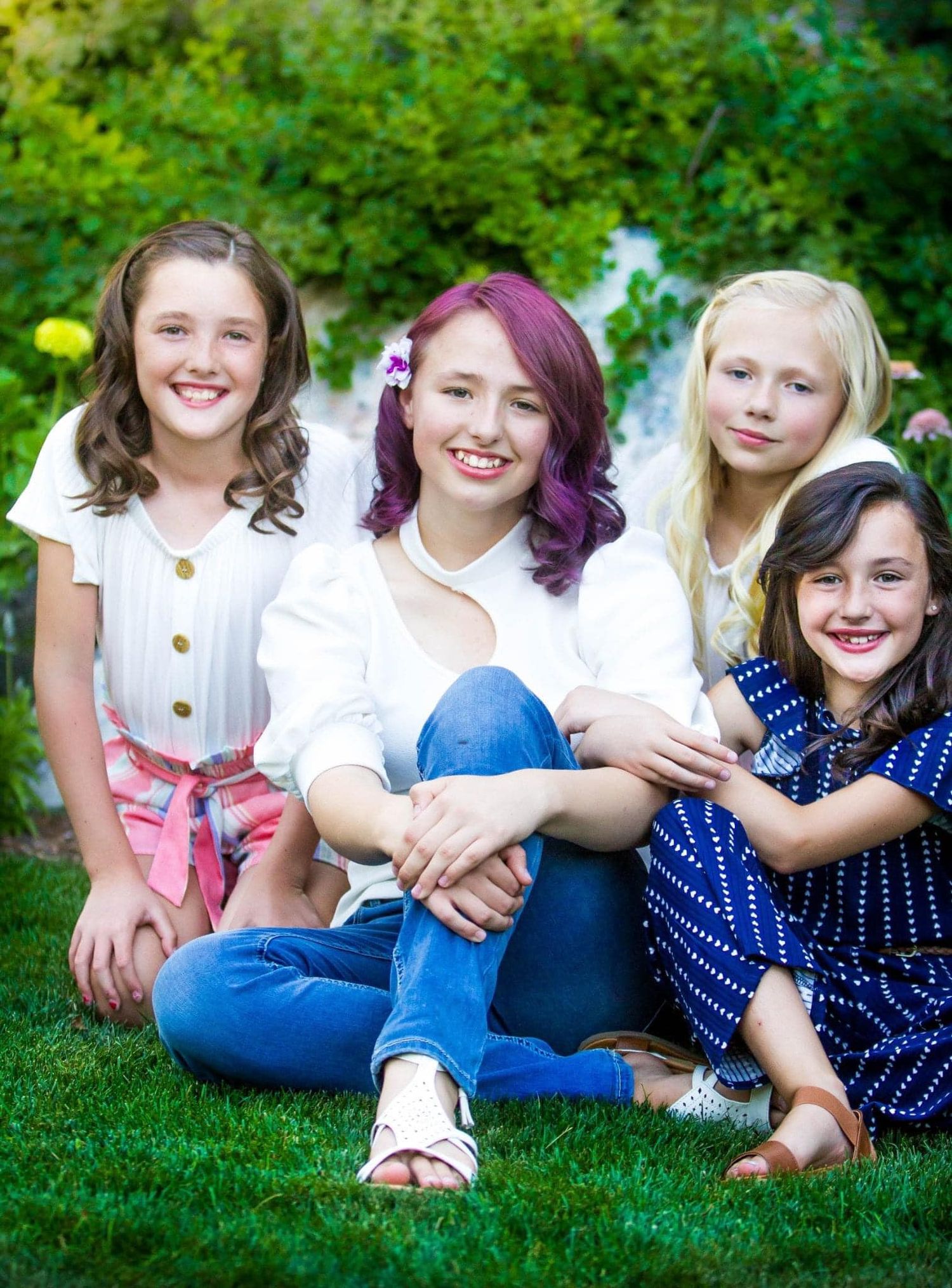 Group sitting casually on grass wearing coordinated blue and white outfits for outdoor photos.