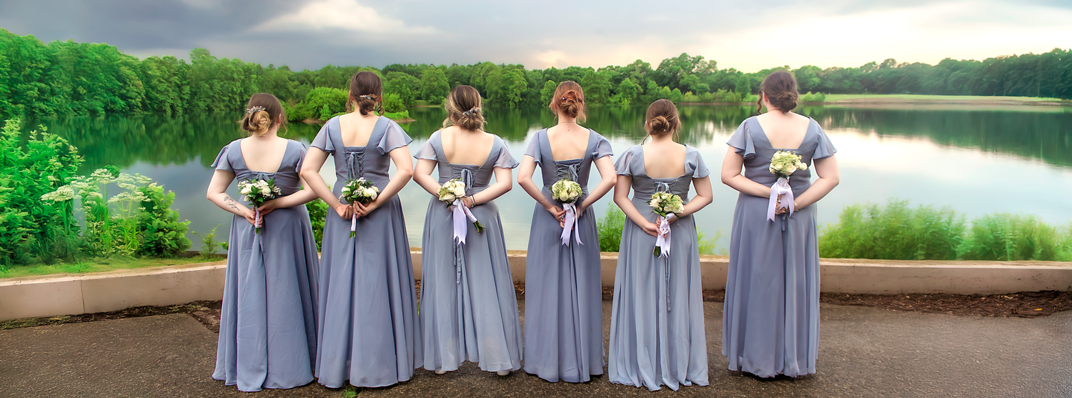 Wedding party lined up in gray attire along a lakeside path.