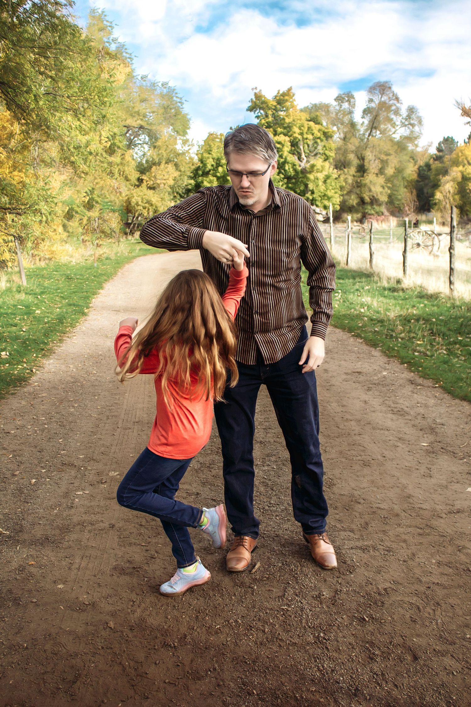 Playful interactions between people on a dirt path surrounded by autumn trees.