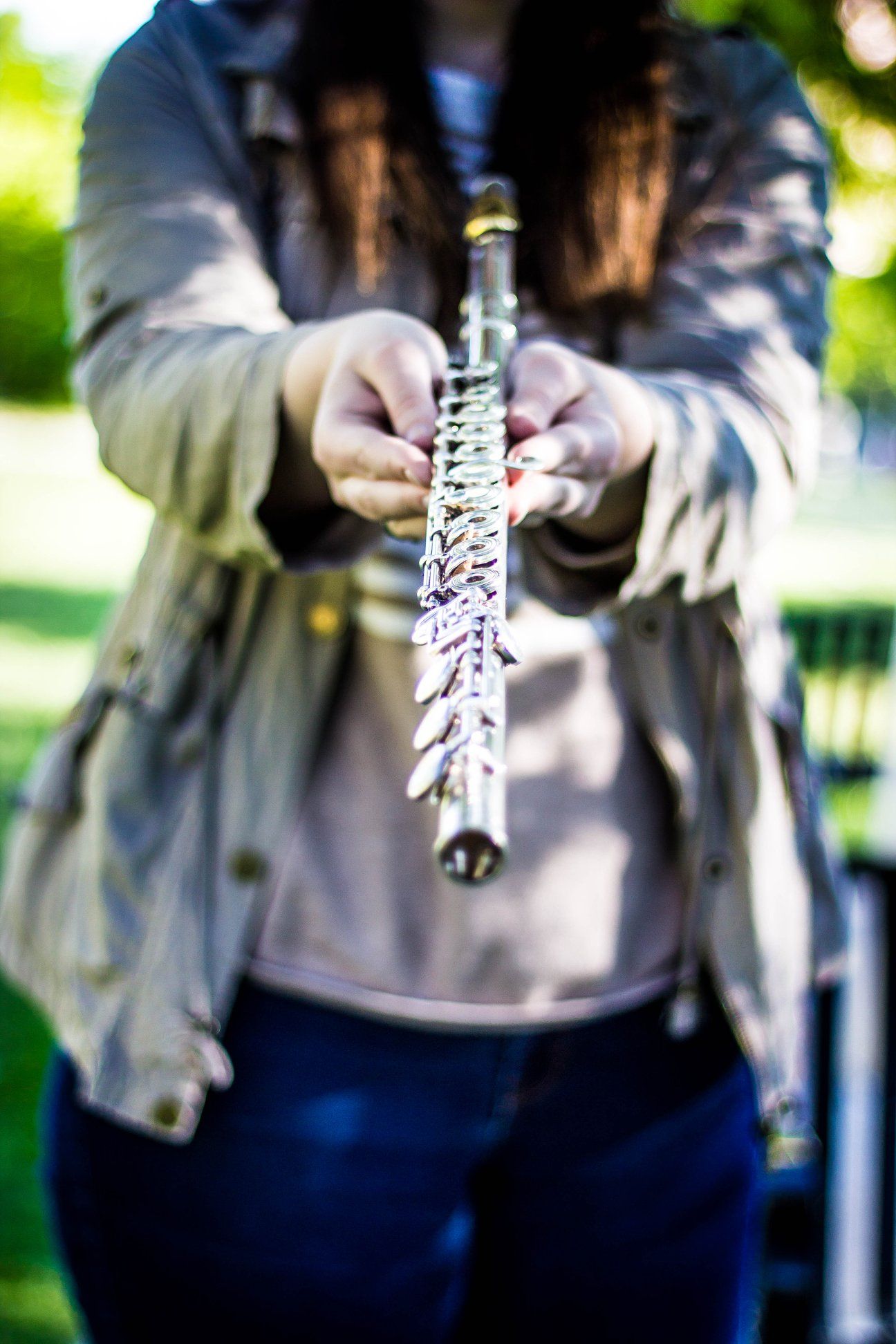 Hands holding and assembling parts of a musical instrument in an outdoor setting.