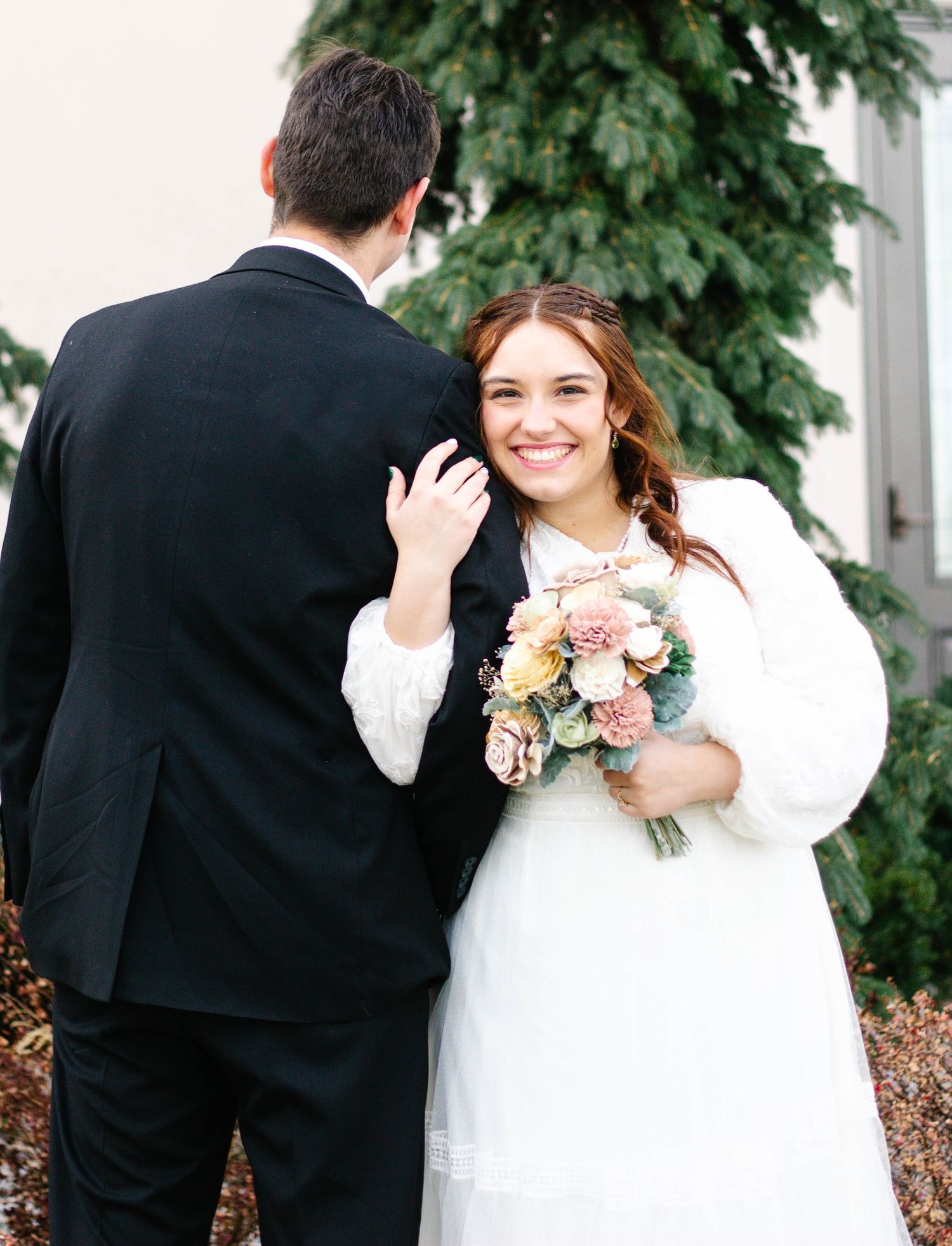 The bride acting coy as she looks on behind her husbands back.