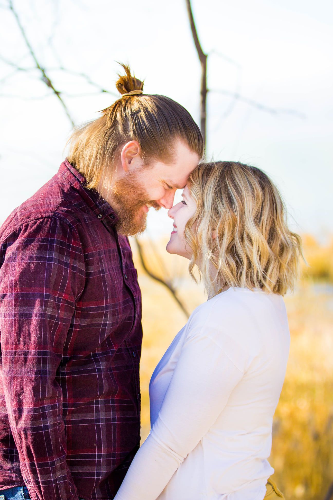 Romantic winter engagement photos with couple in plaid and cream colored outfits.