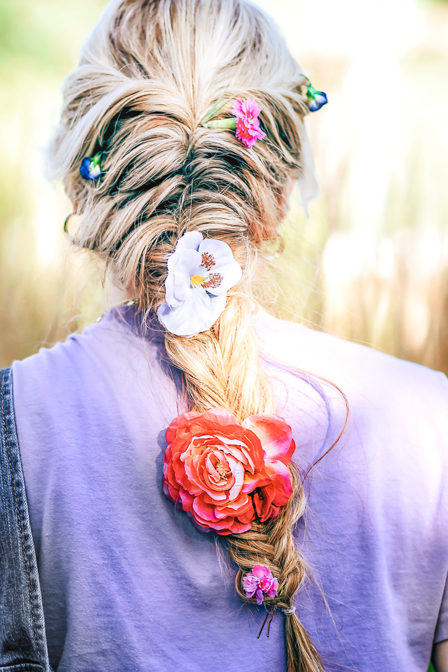 Close-up of braided hair decorated with colorful butterflies and coral flower accessories.