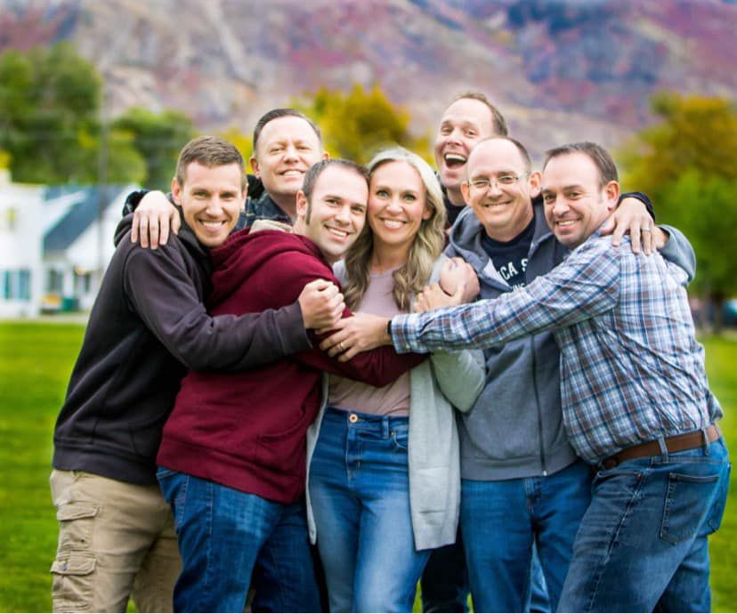 Group portrait against colorful mountain backdrop in casual attire.