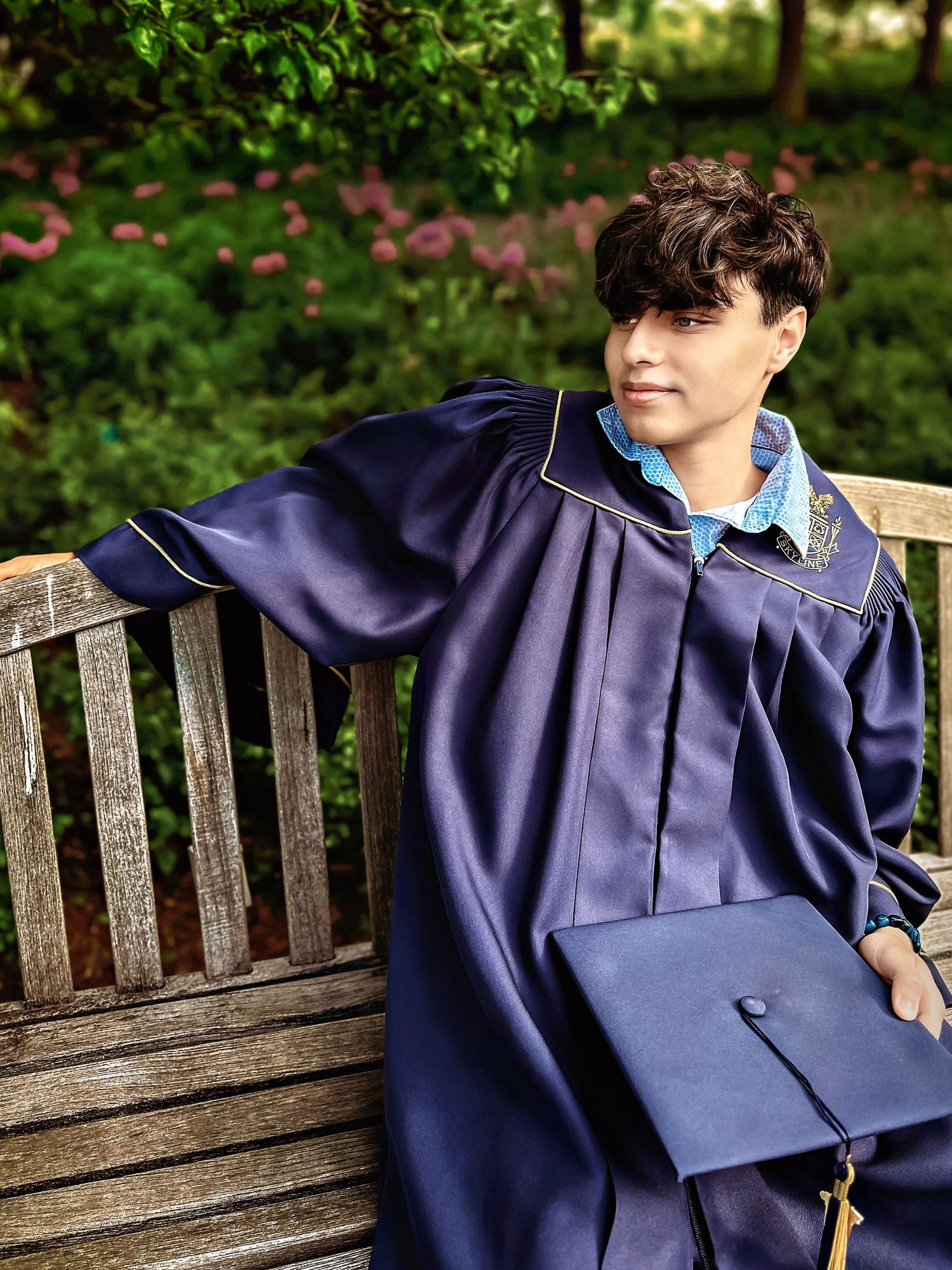 Close-up shots of navy blue graduation cap and gown on wooden bench.