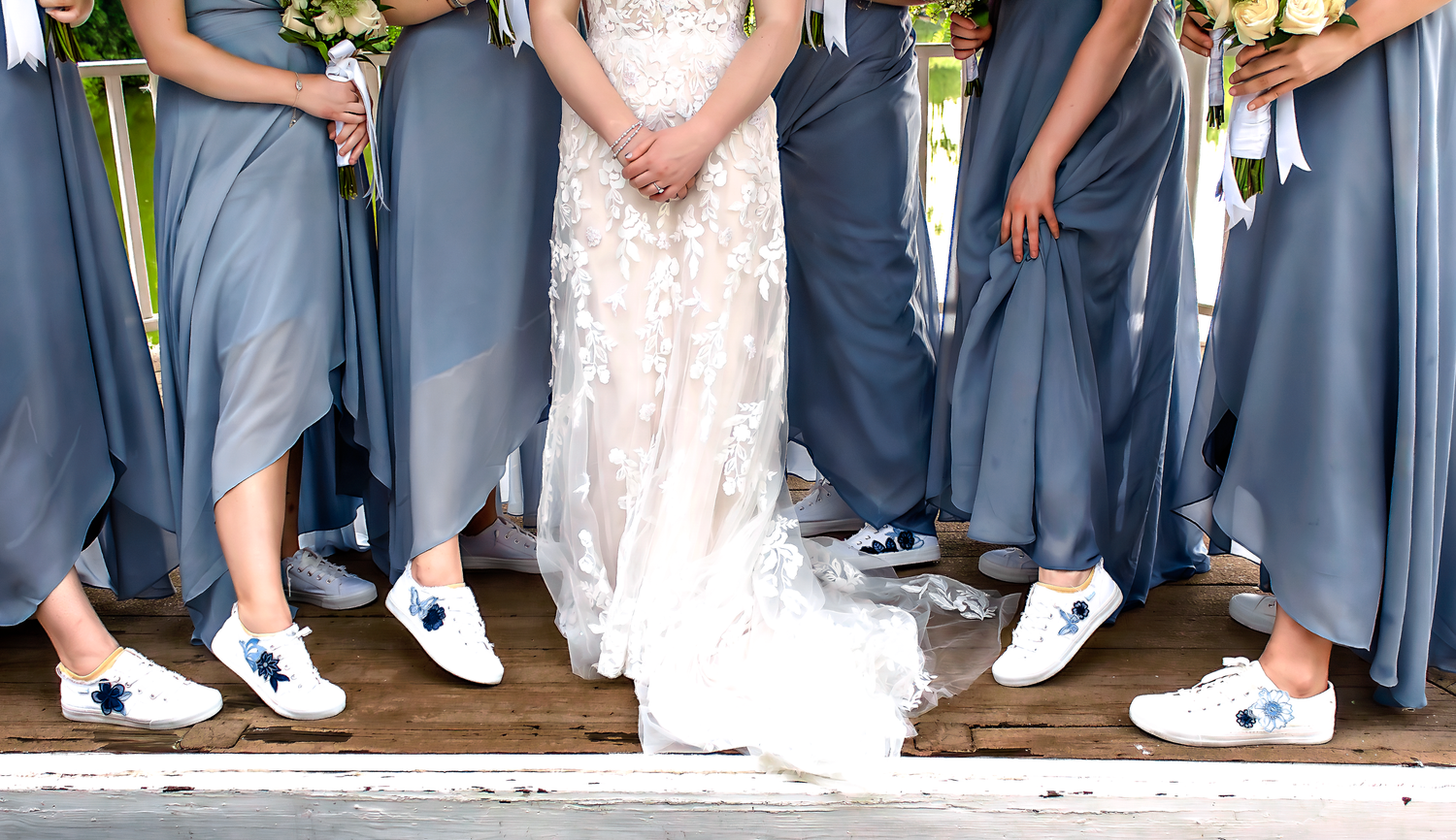 Wedding party members in navy blue attire pose together on stone steps.