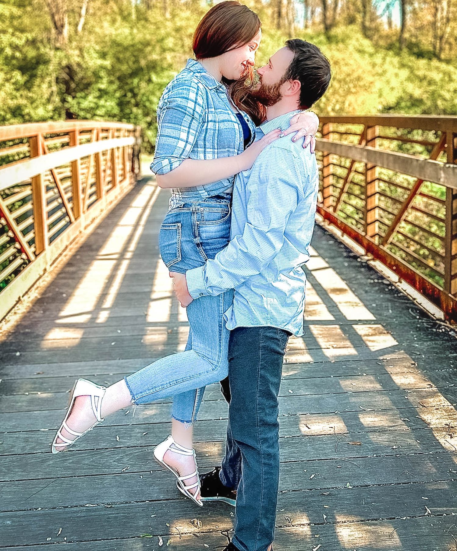 Couple shares romantic moments on wooden bridge during casual photo session.