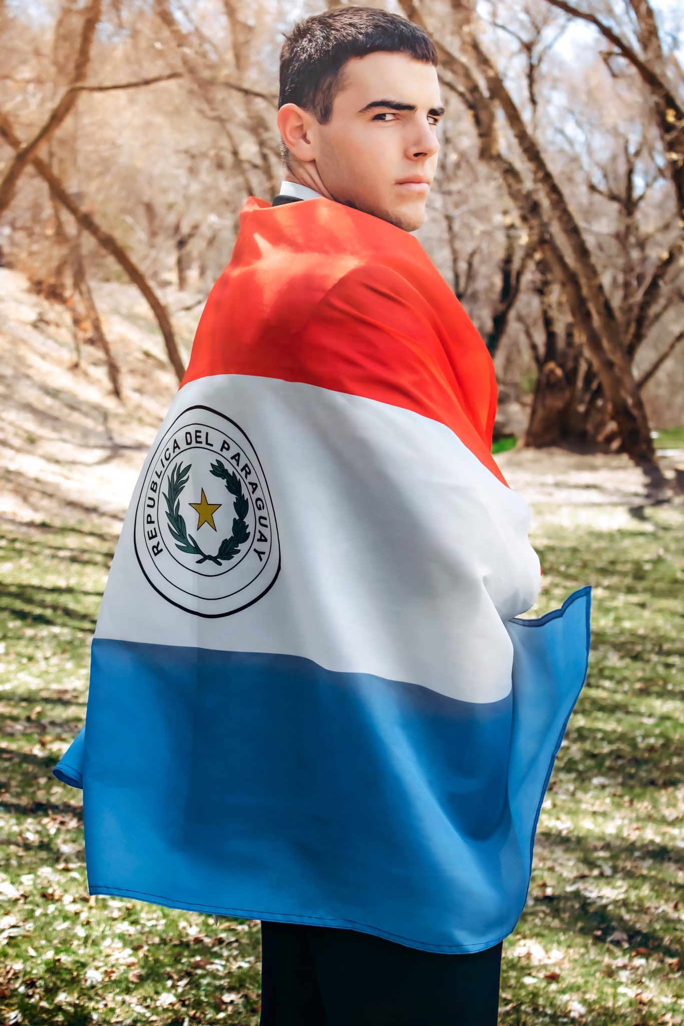 Red, white and blue Paraguayan flag displayed against natural outdoor background.