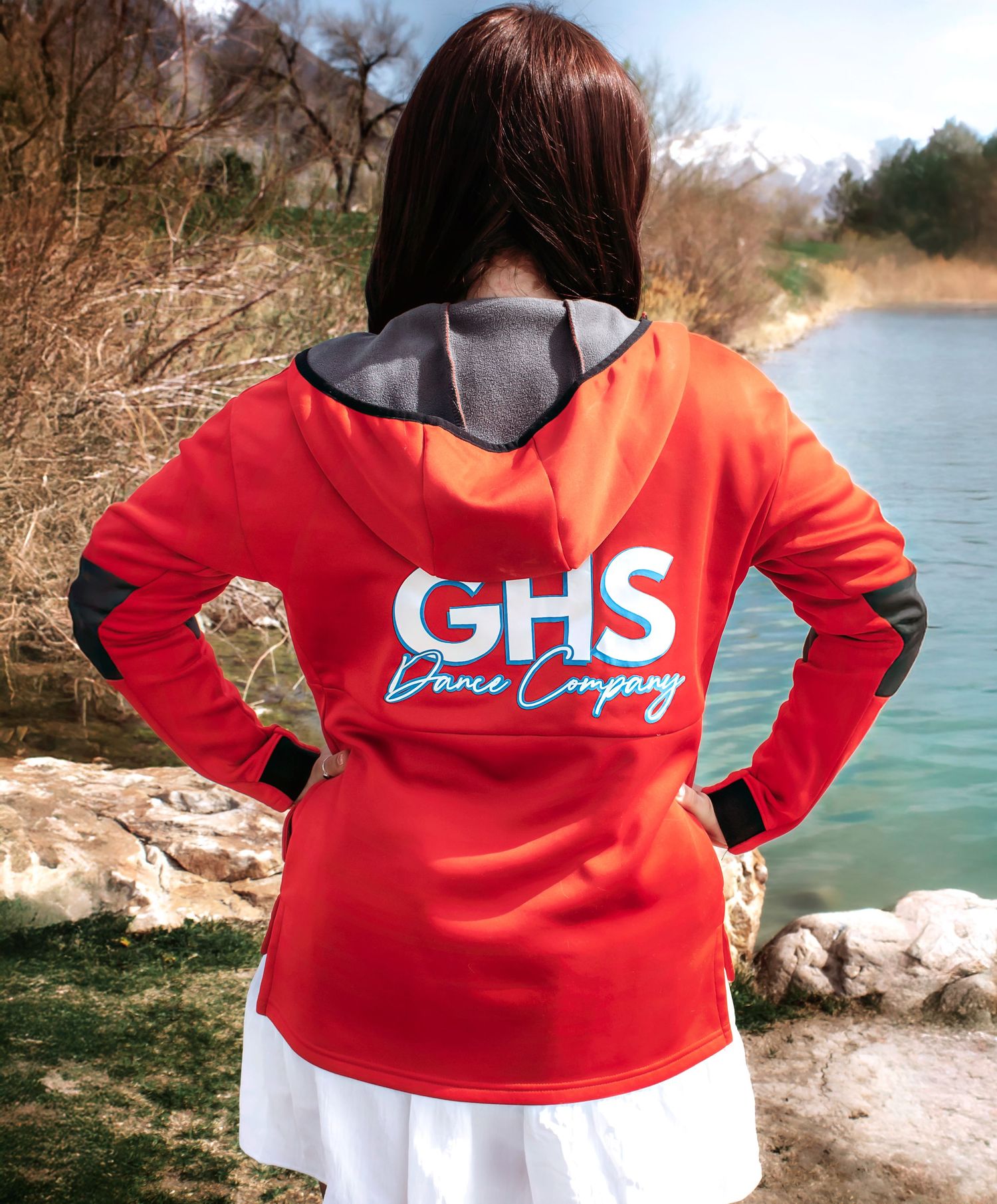 Back view of person wearing red GHS Dance Company hoodie near water.
