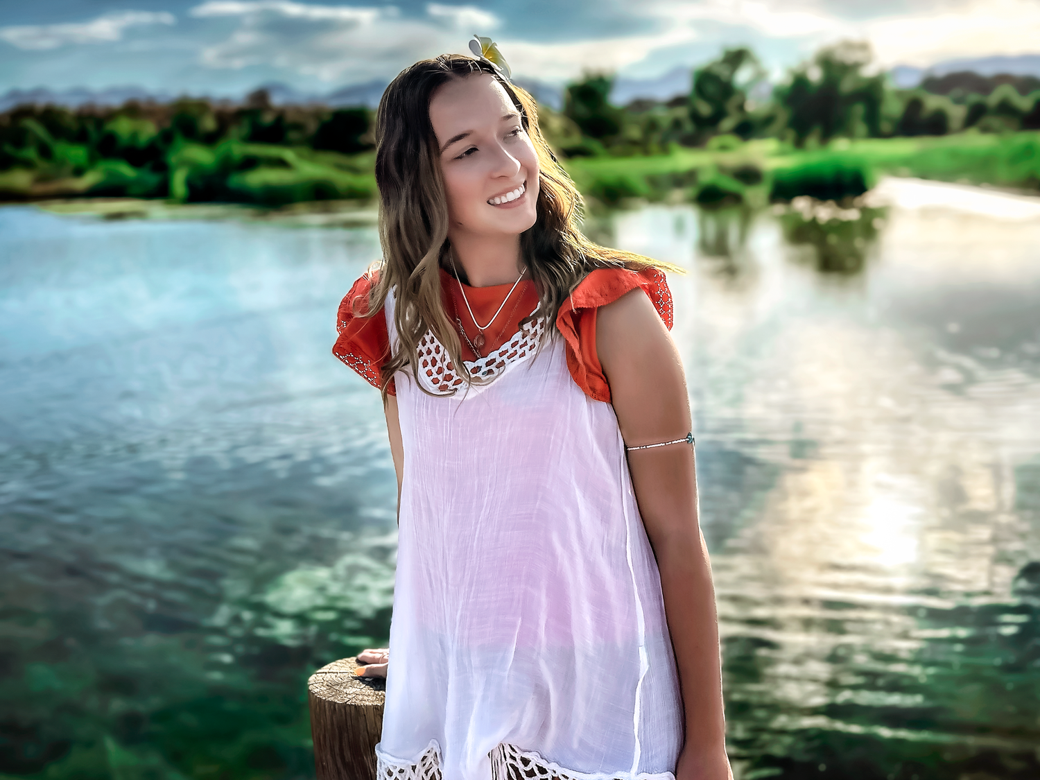 A serene waterfront photoshoot featuring someone in a white summer dress with coral details.