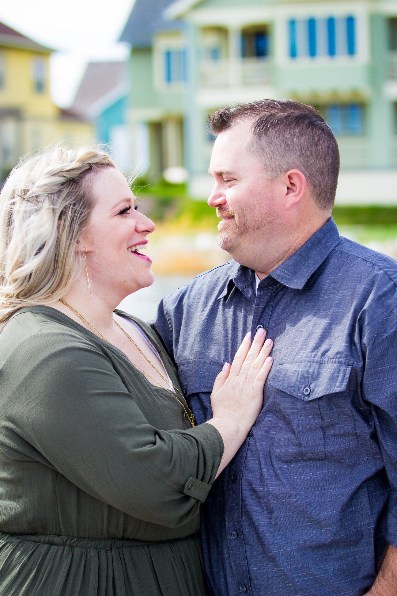 Couple sharing playful and candid moments in front of coastal homes.