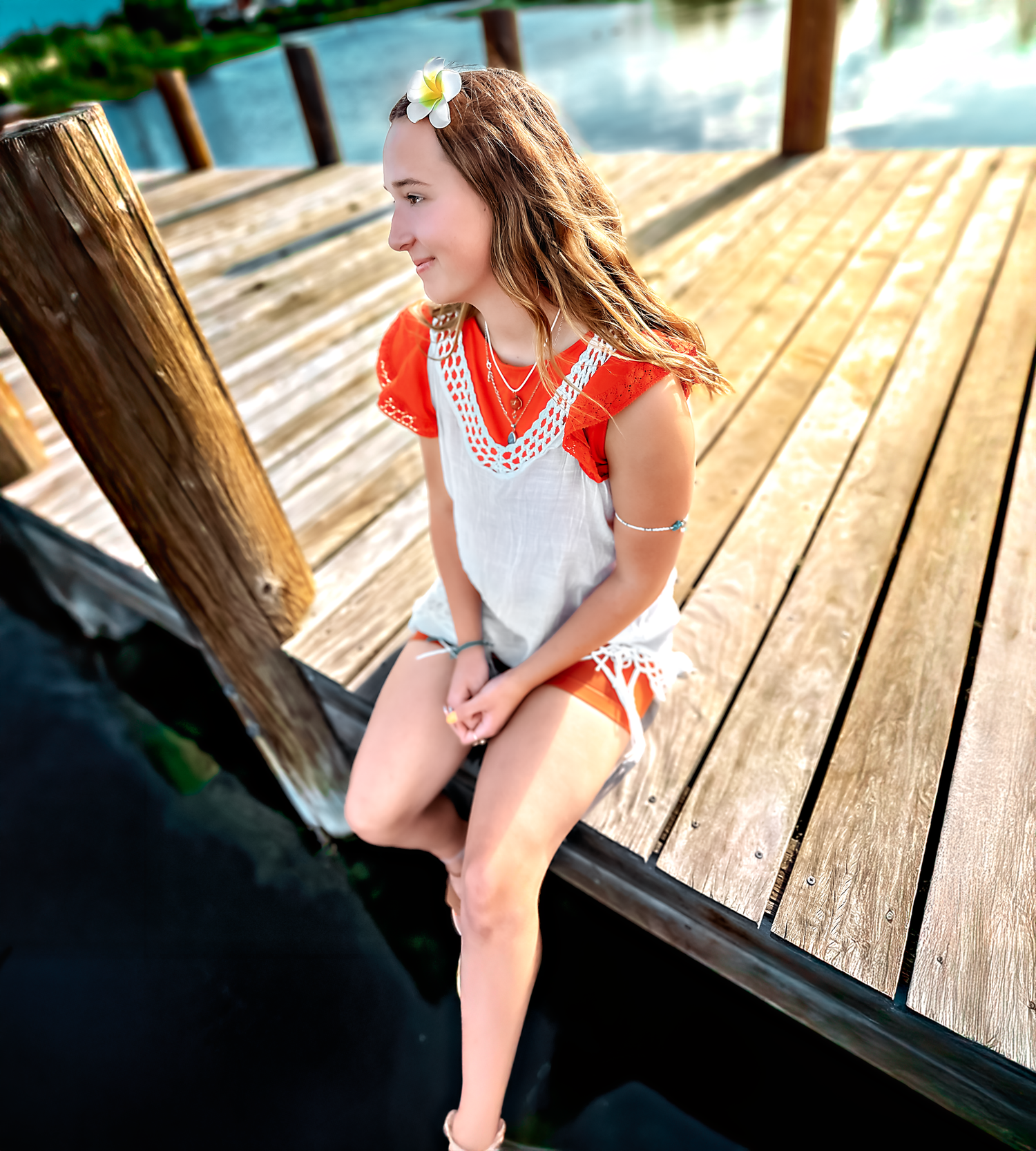 Someone sits thoughtfully on a wooden pier overlooking a serene lake.