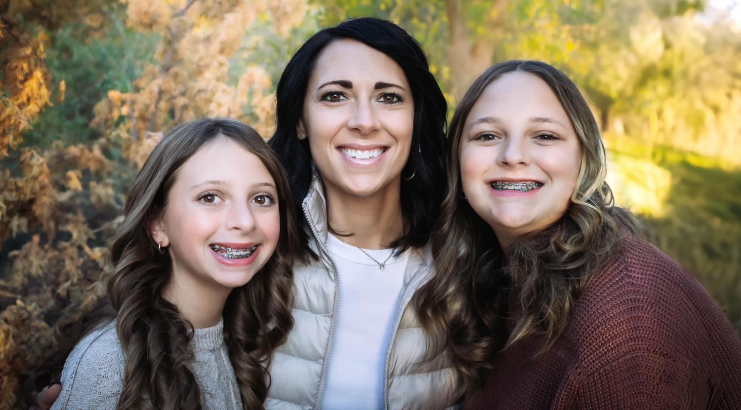 Group portrait of women in casual attire against autumn foliage background.