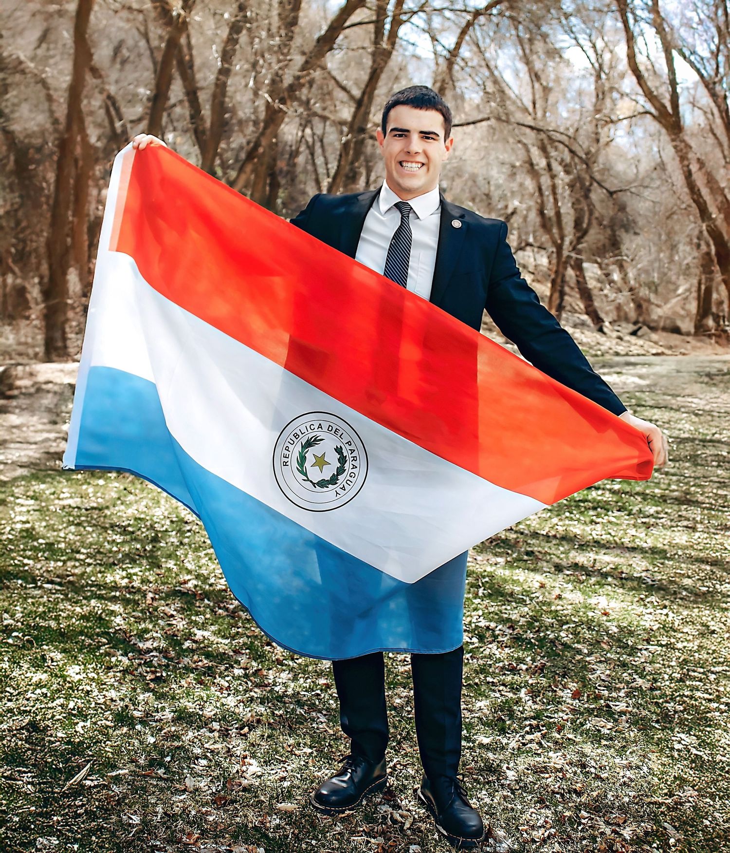 Person in formal attire proudly displays the Paraguayan flag outdoors.