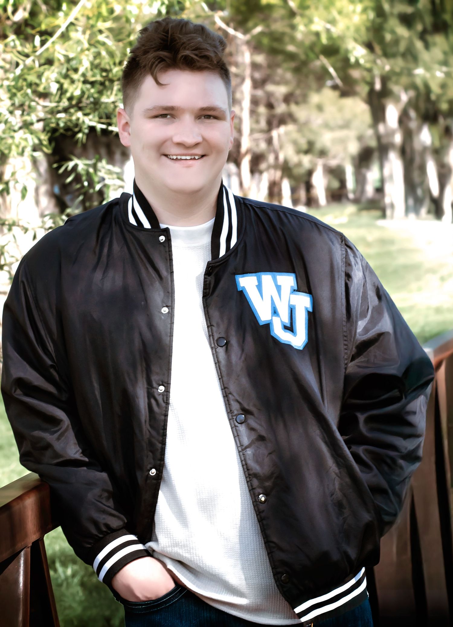 Student wearing a black and white varsity letterman jacket with WJ logo outdoors.