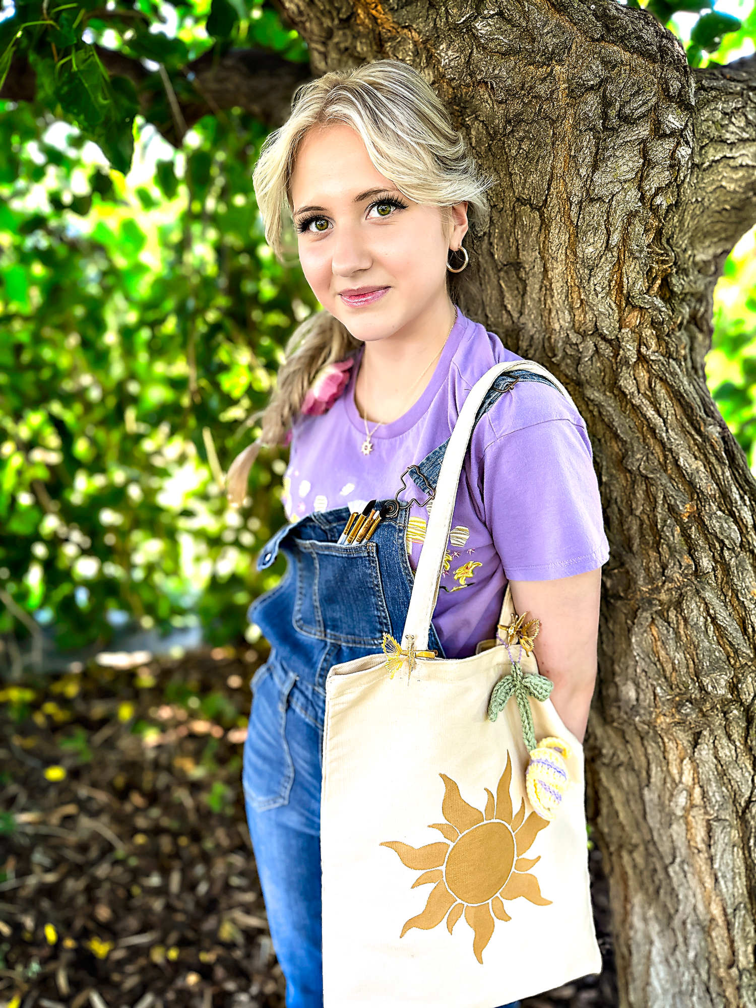 Casual outdoor portraits with a sun-decorated tote bag against a tree backdrop.