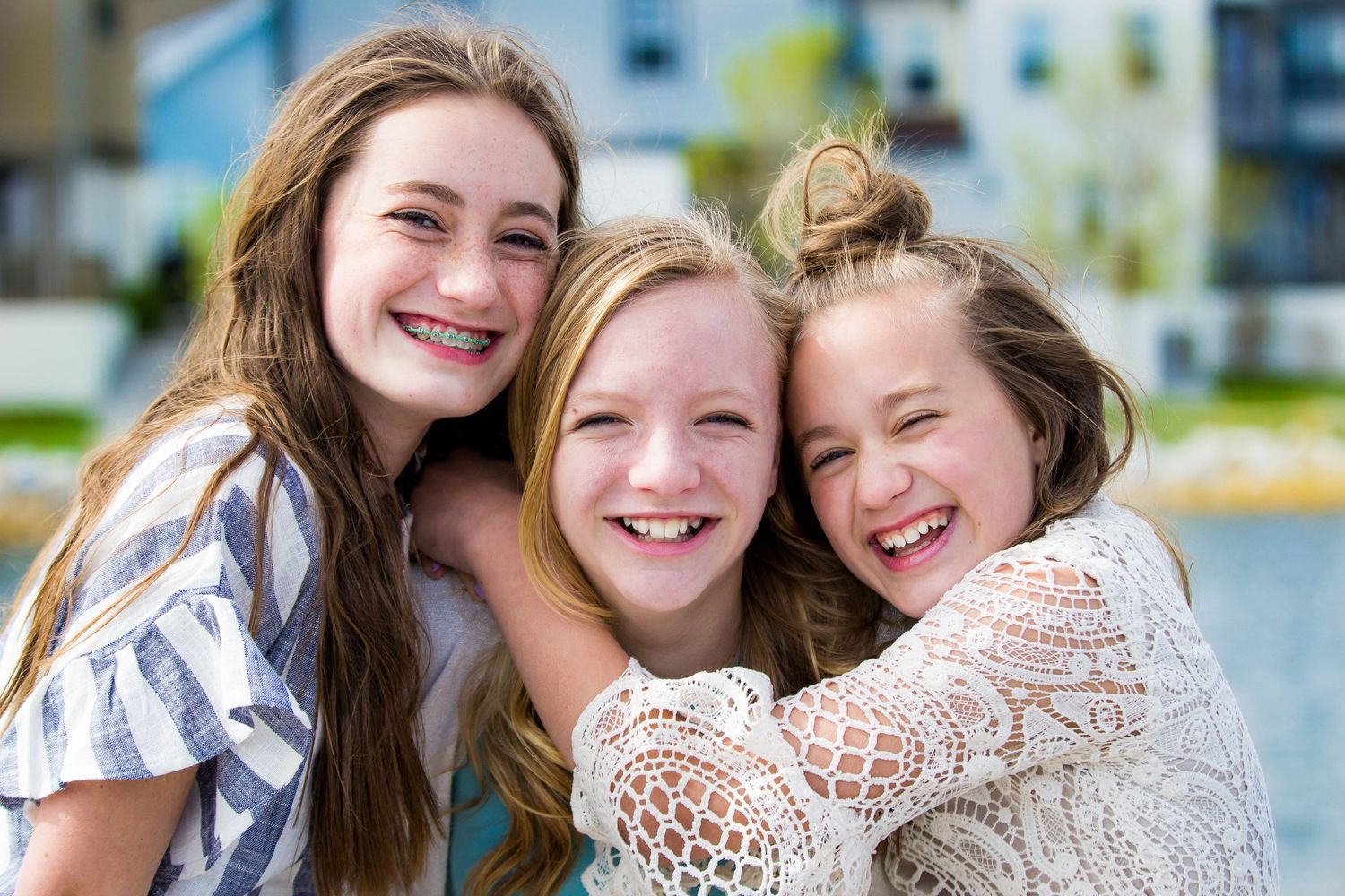 Three people sharing joyful laughter while sitting together outdoors.