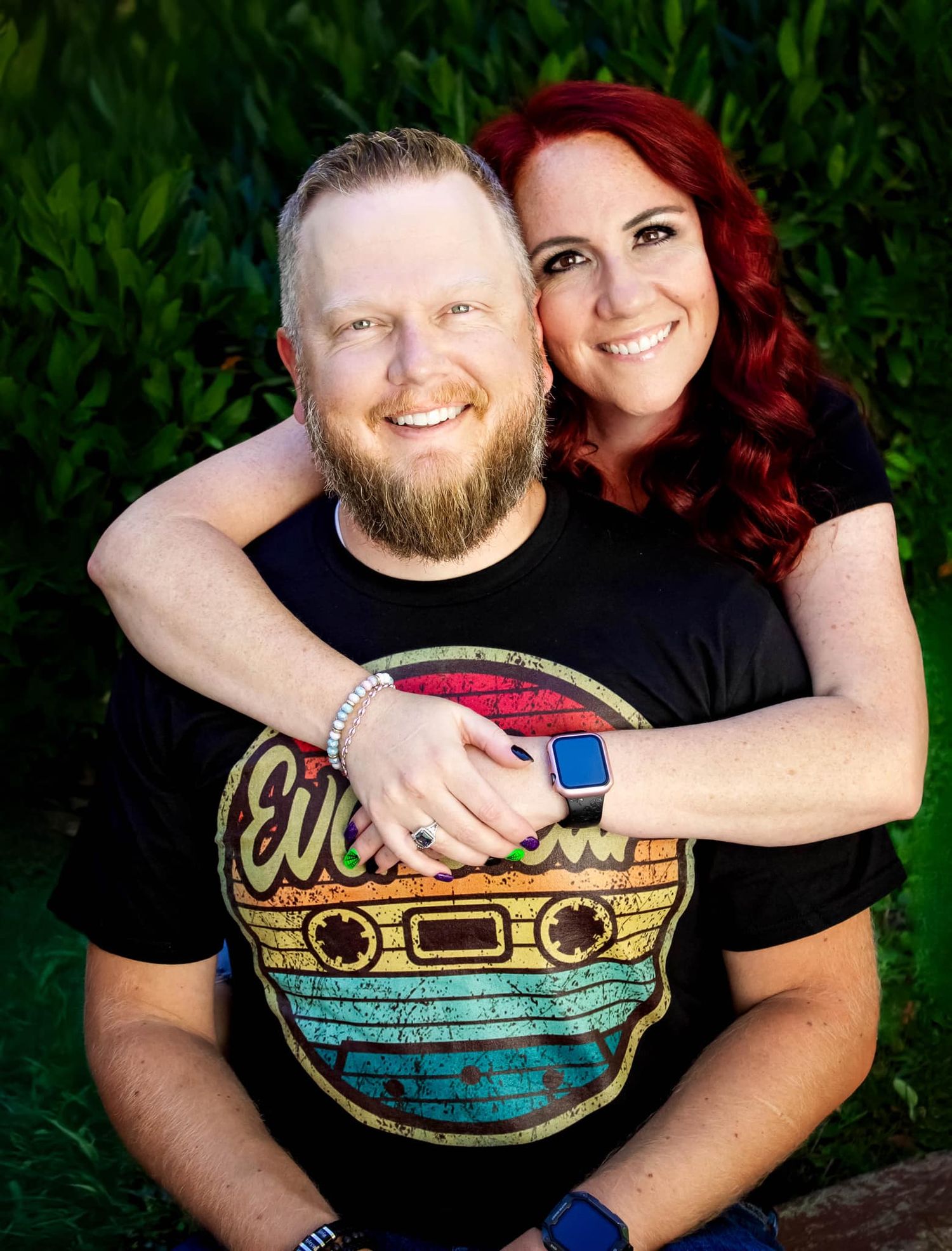 Couple in casual attire share loving embraces against a green natural background.