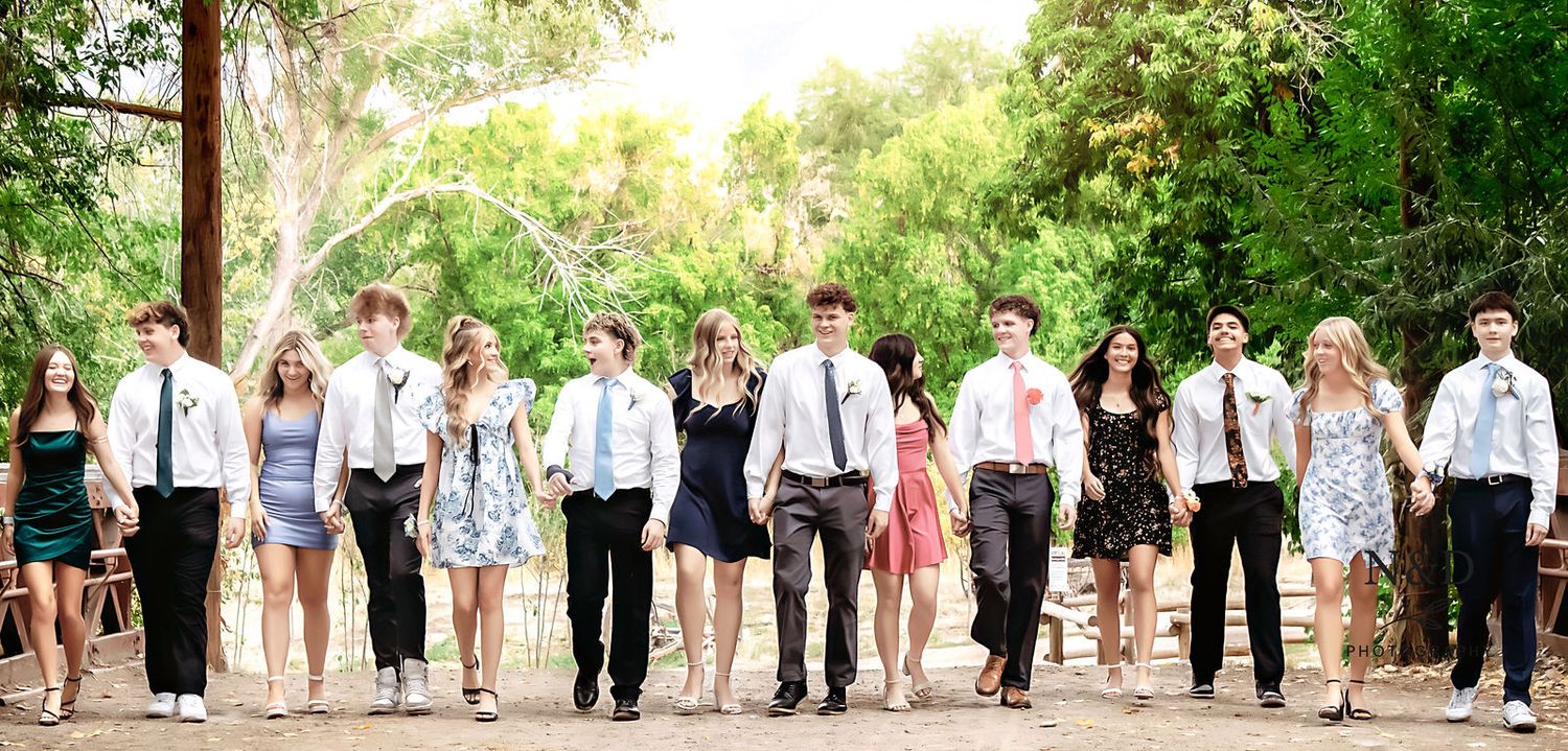 Large wedding party group photo with coordinated formal attire in outdoor garden setting.