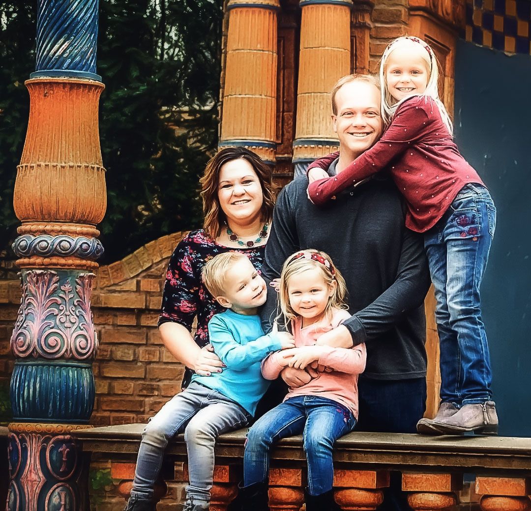A family poses together on decorative steps with ornate columns.