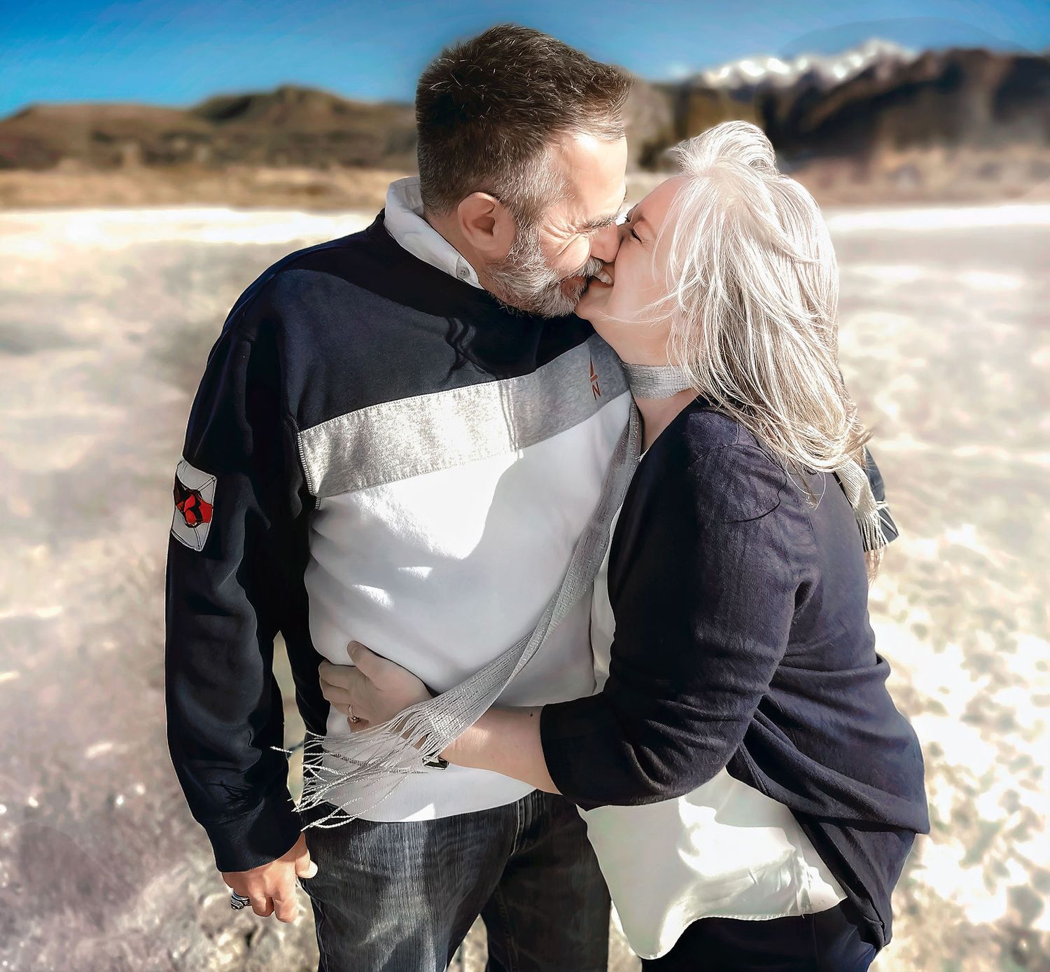 Candid engagement photos showing couple embracing in snowy winter setting.