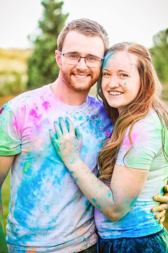 Couple covered in colorful powder paint embrace during a fun outdoor photo session.