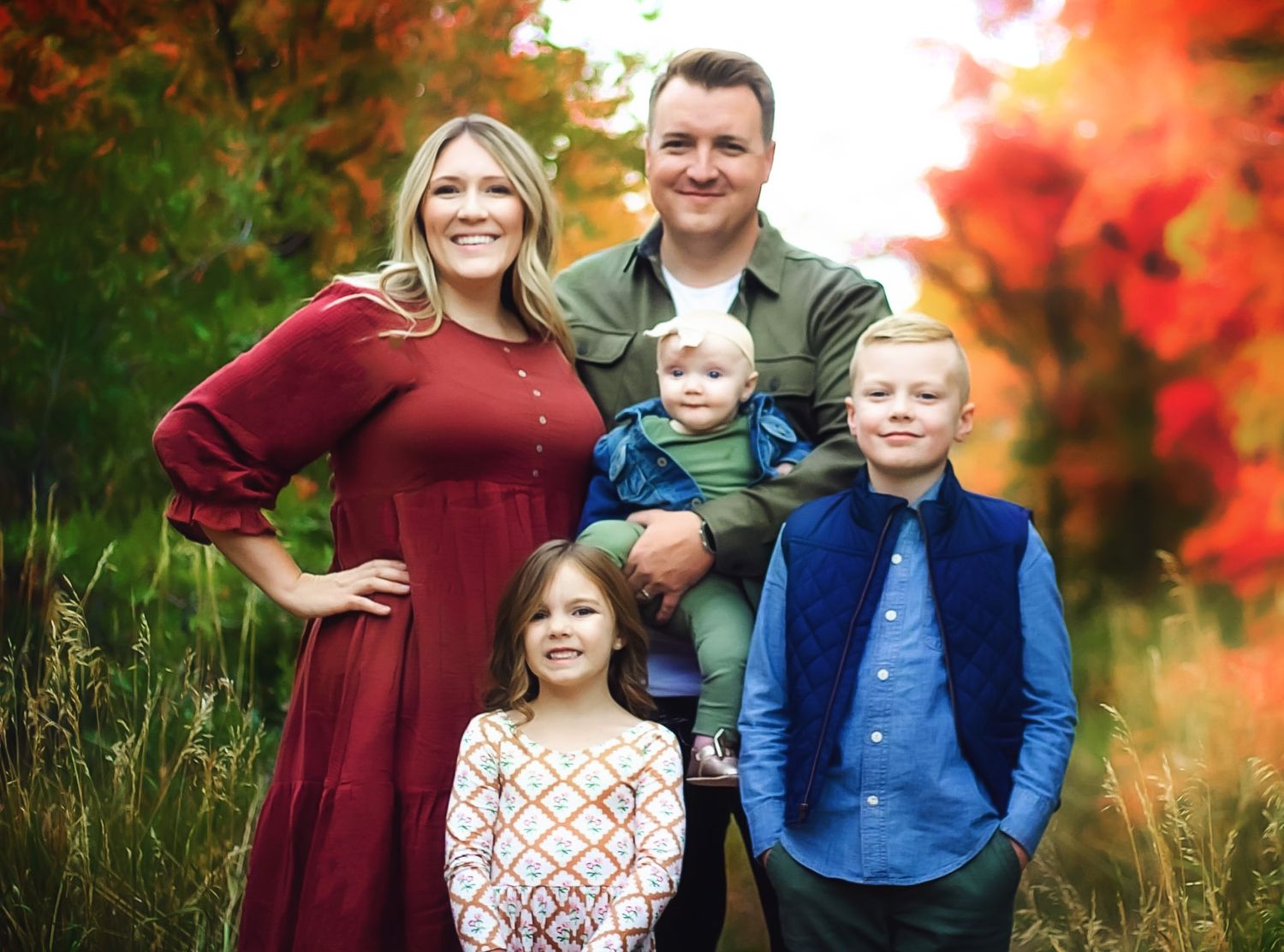 A family of five poses against vibrant fall foliage during an autumn photo session.