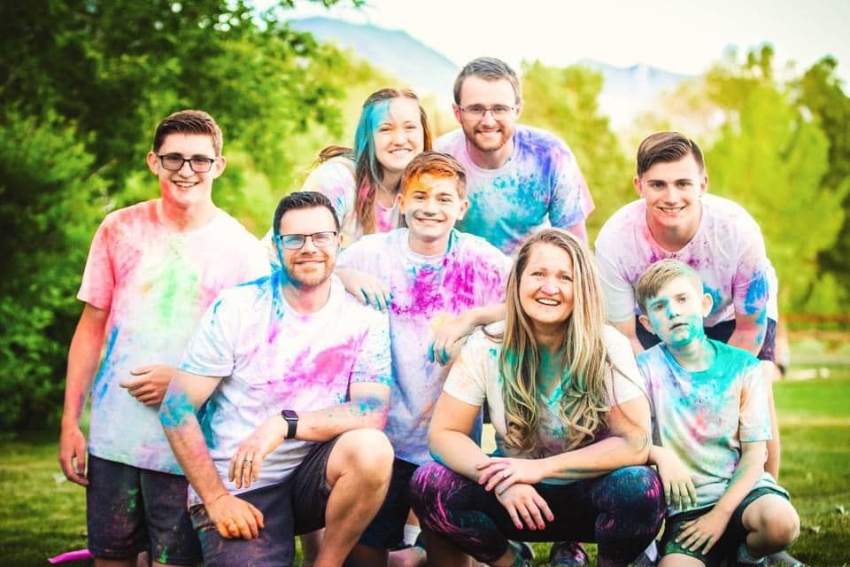 Playful group photo with colorful powder paint during outdoor celebration.